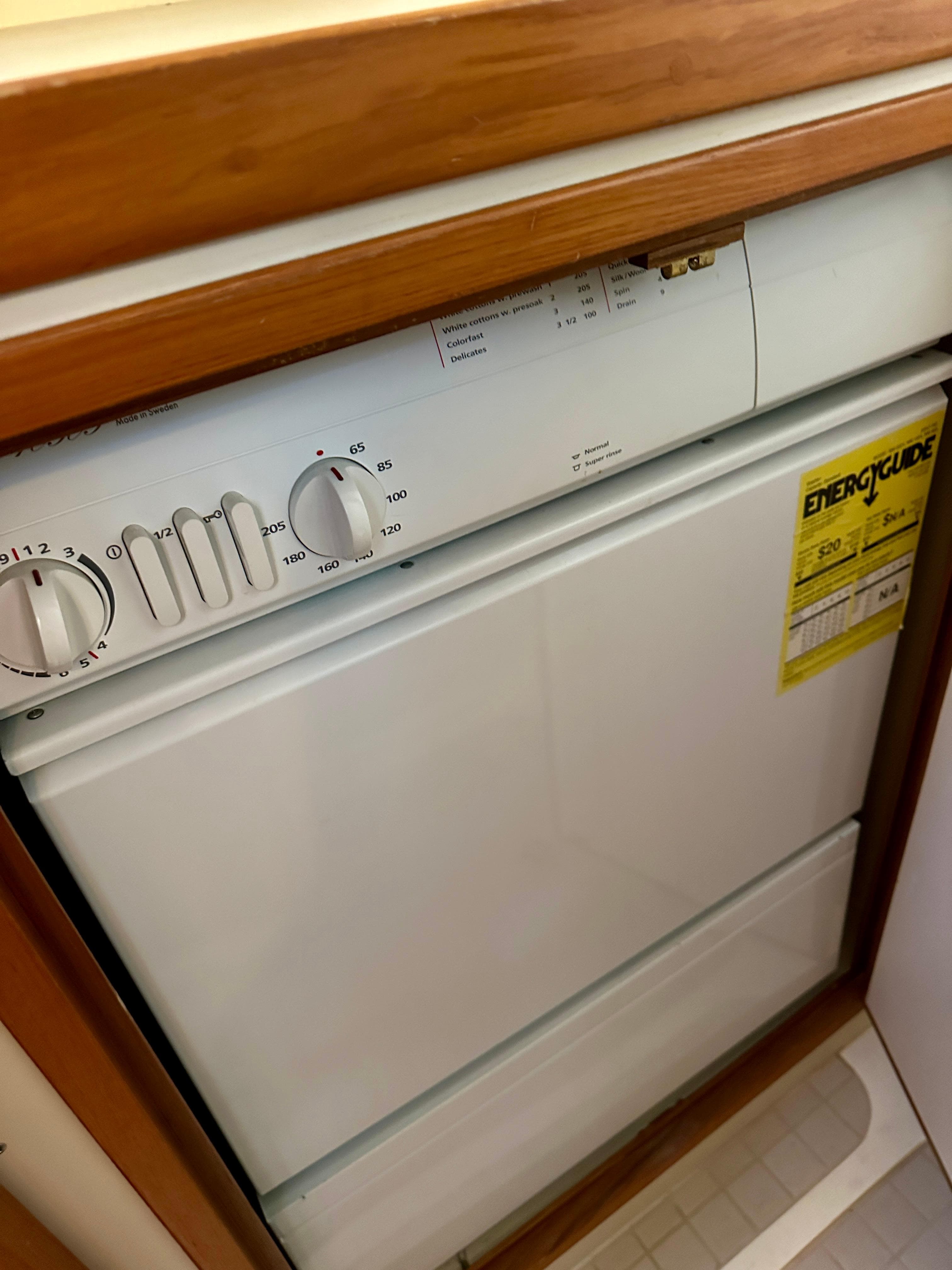 Built-in dishwasher in 1997 Sabre Cockpit Motor Yacht, featuring wood trim and energy guide label.