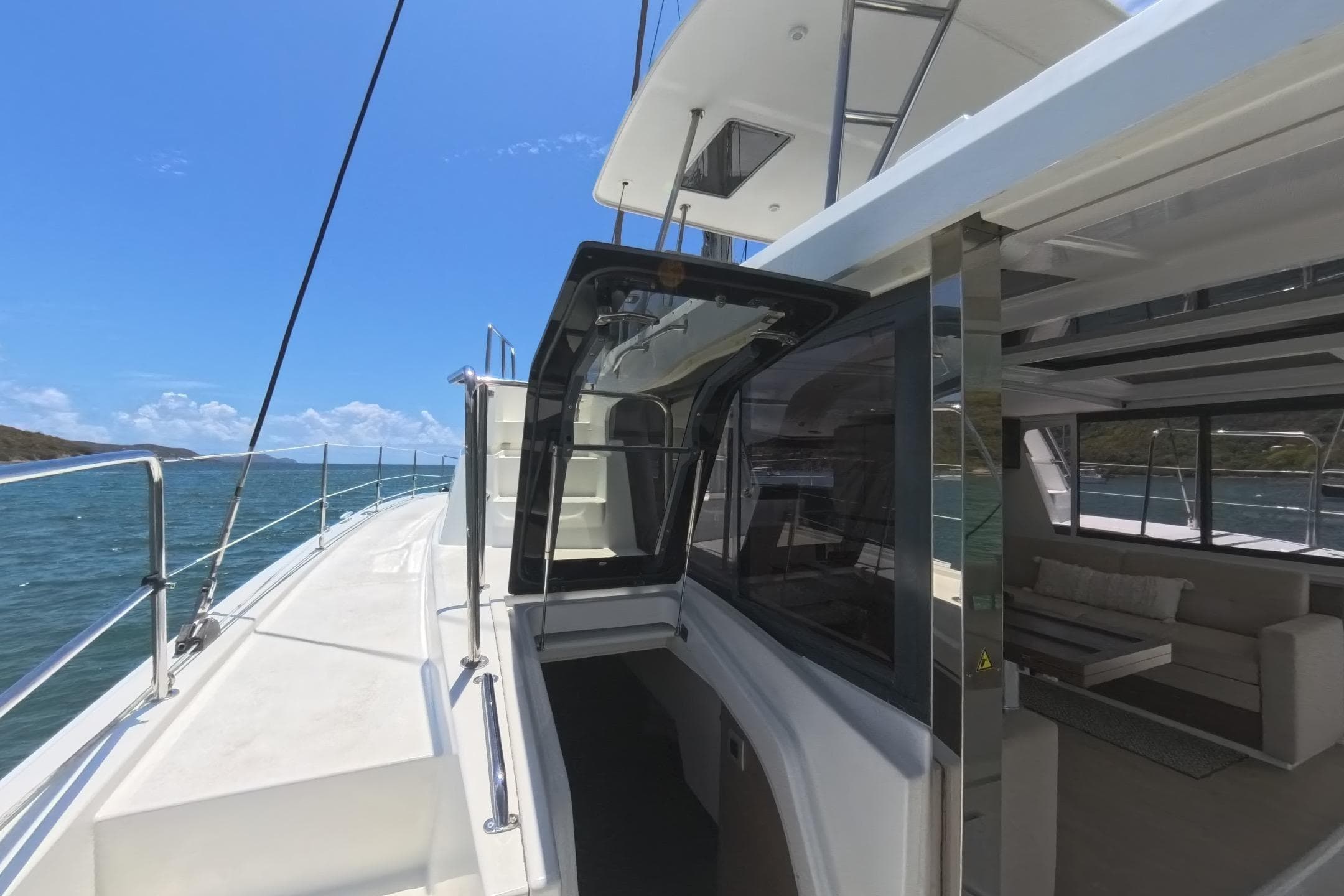 2022 Bali 4.6 yacht deck with open cabin, ocean view, and clear blue sky.