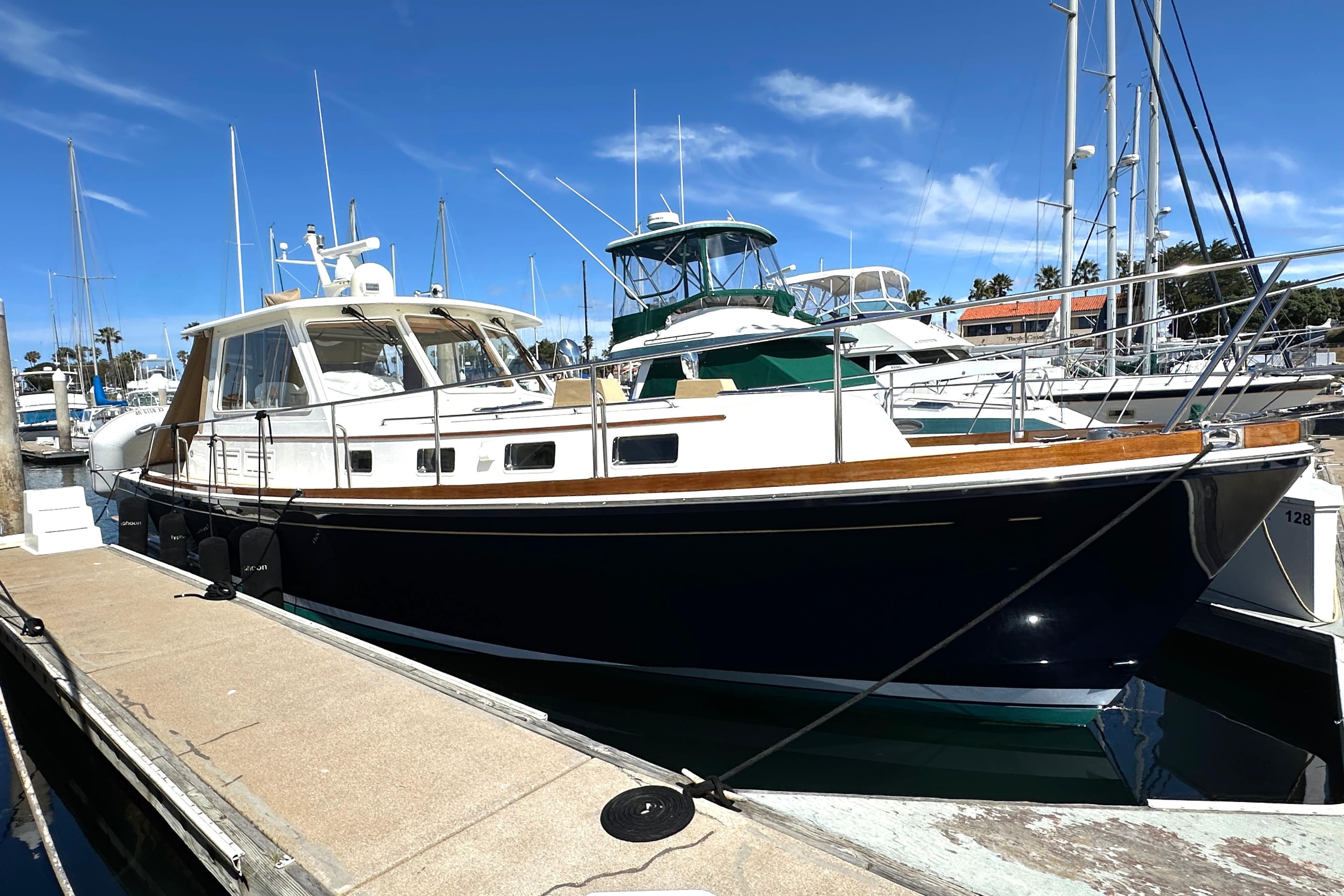 2003 Grand Banks 43 Eastbay HX yacht docked at marina under clear blue sky.