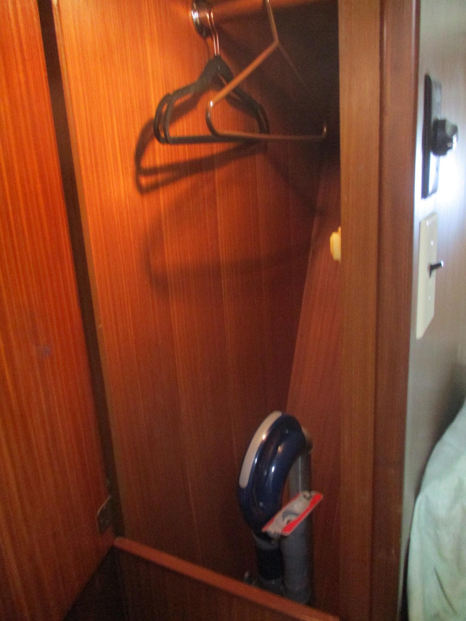 Wooden closet interior on 1986 Hatteras 43 Double Cabin with hangers and vacuum cleaner.