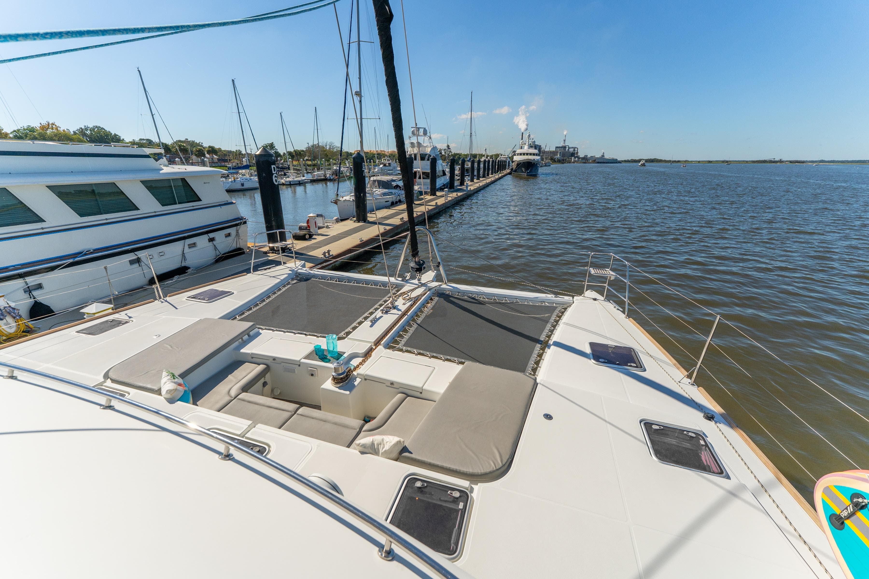 Lagoon 560 catamaran docked at marina, showcasing spacious deck and serene water view.