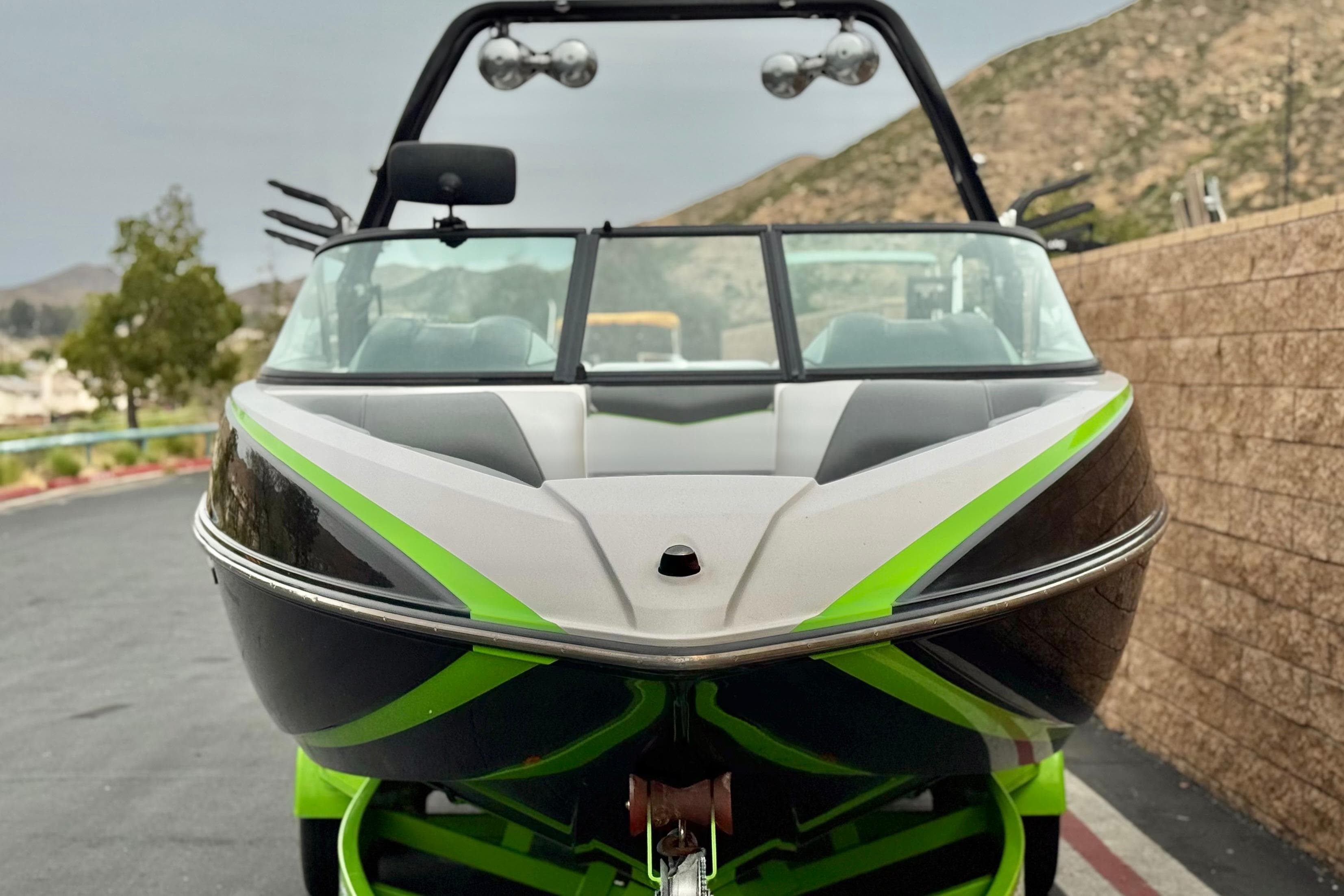 2016 Moomba Craz boat with green accents, parked near a stone wall.