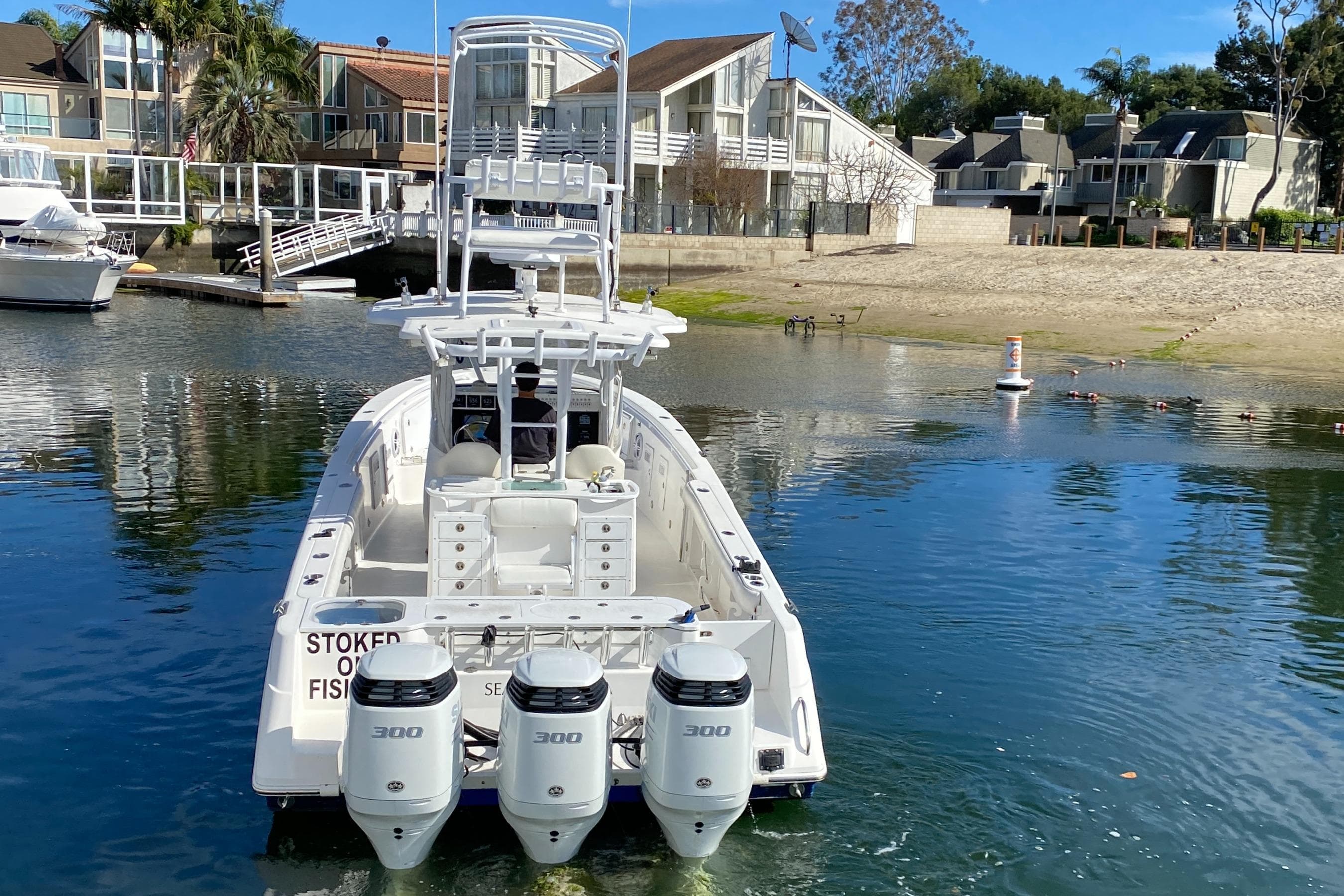 2008 Everglades 355 Center Console boat with triple 300 horsepower engines docked near waterfront homes.
