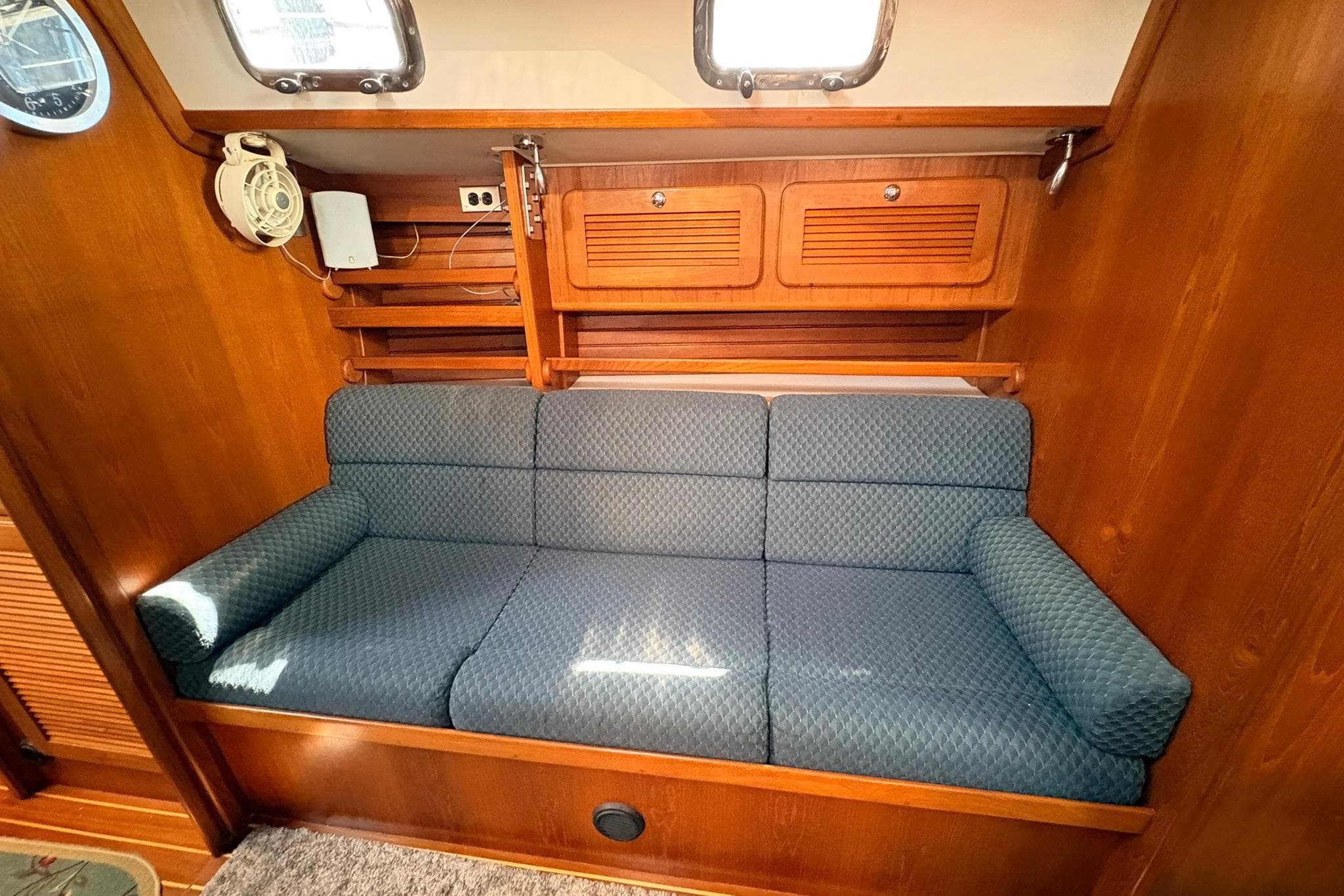 Cozy seating area in 2009 Caliber 40LRC SE yacht with wooden interior and blue cushions.