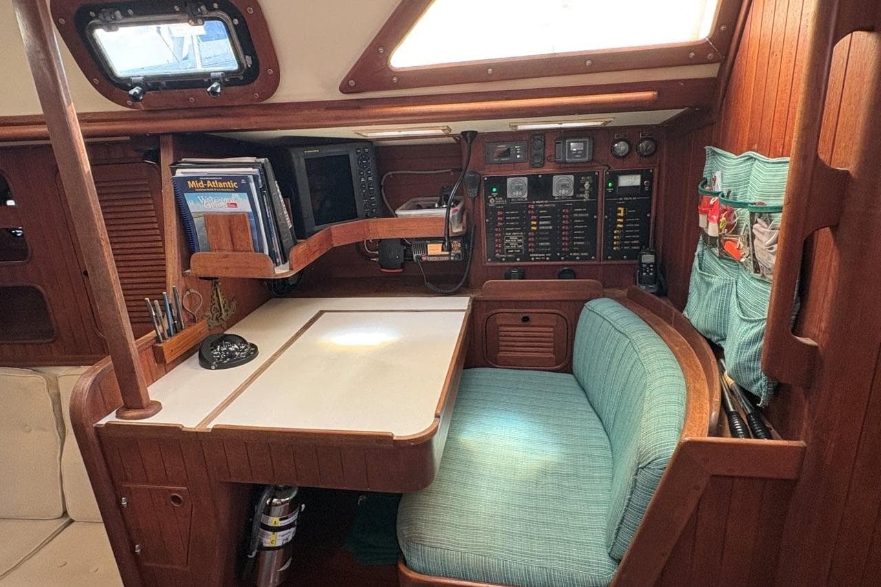 Cozy navigation station in 1981 Norseman 447 sailboat with wood paneling and teal seating.