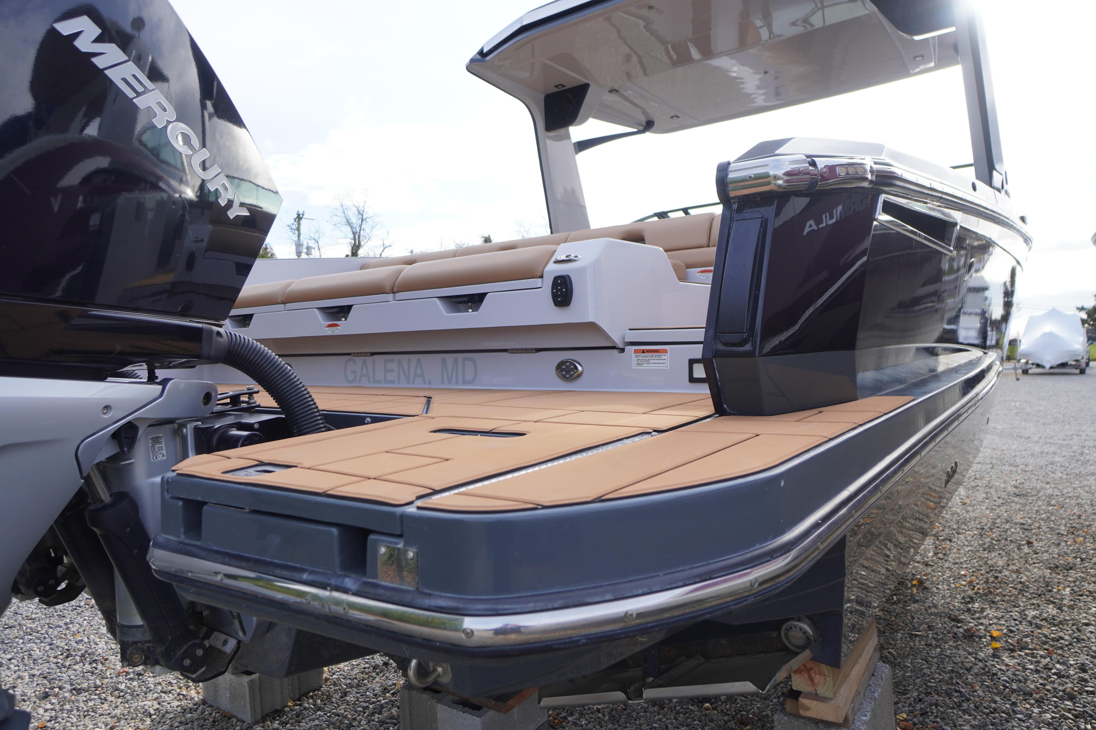 2020 Aviara AV32 OB boat with Mercury engine, docked on gravel.