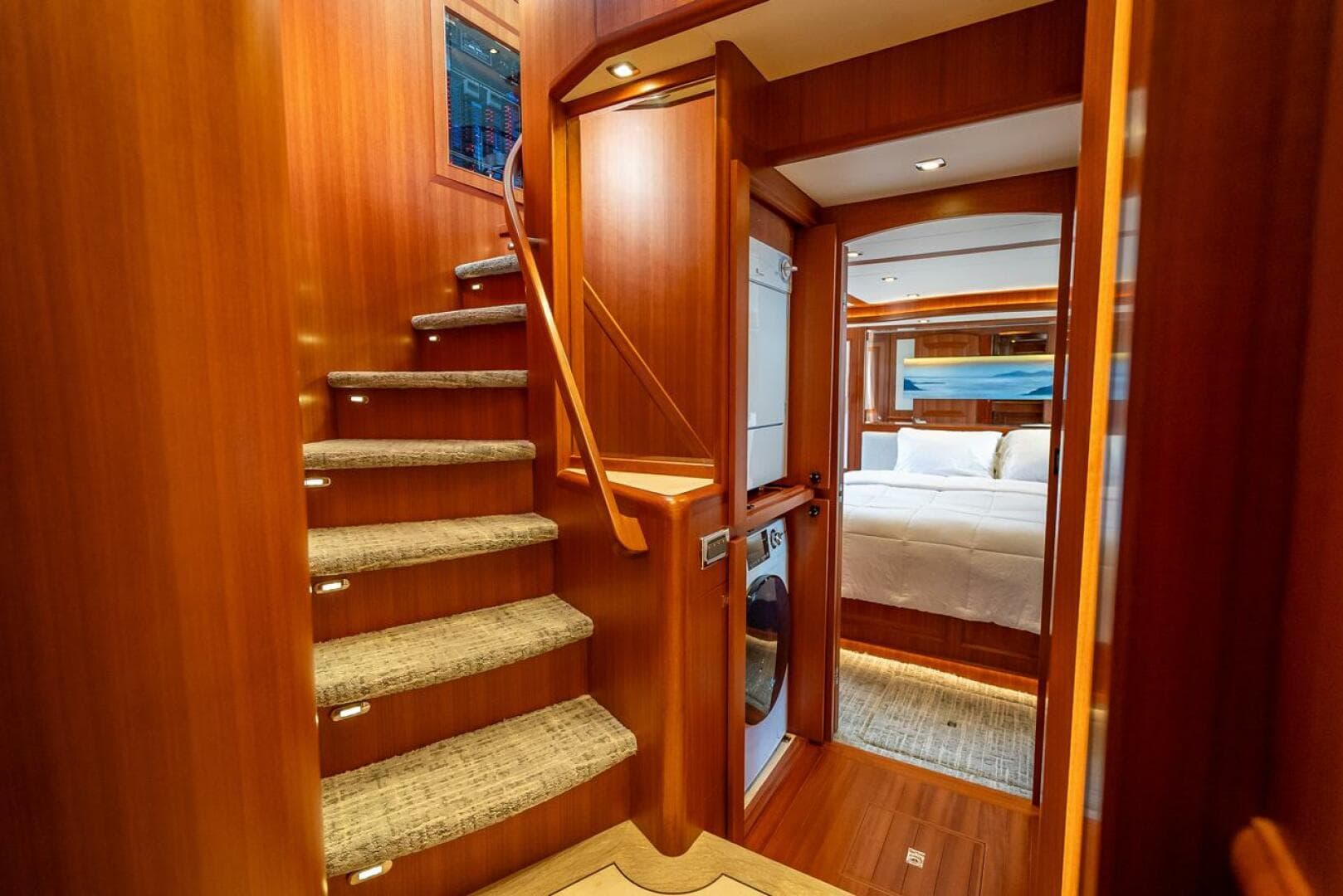 Luxurious interior of 2022 Hampton 658l Endurance yacht with wooden staircase and cozy bedroom.