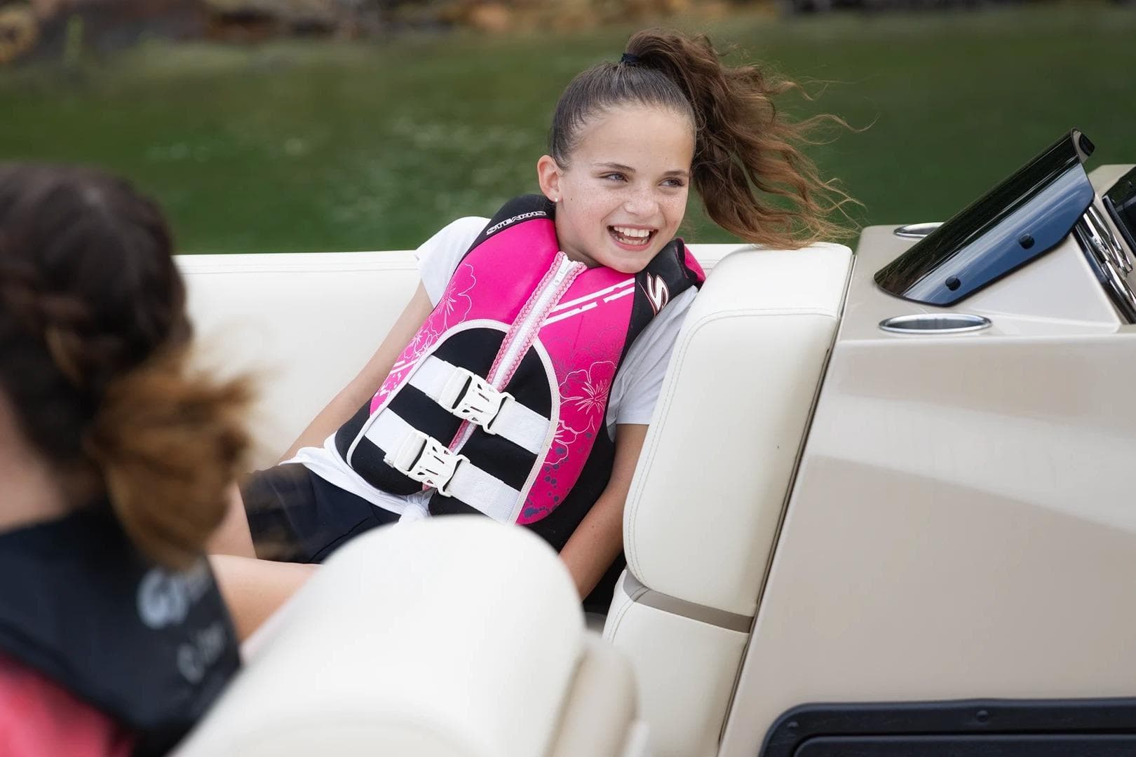 Girl smiling on a 2026 SunCatcher Elite 322 SR boat, wearing a pink life jacket.