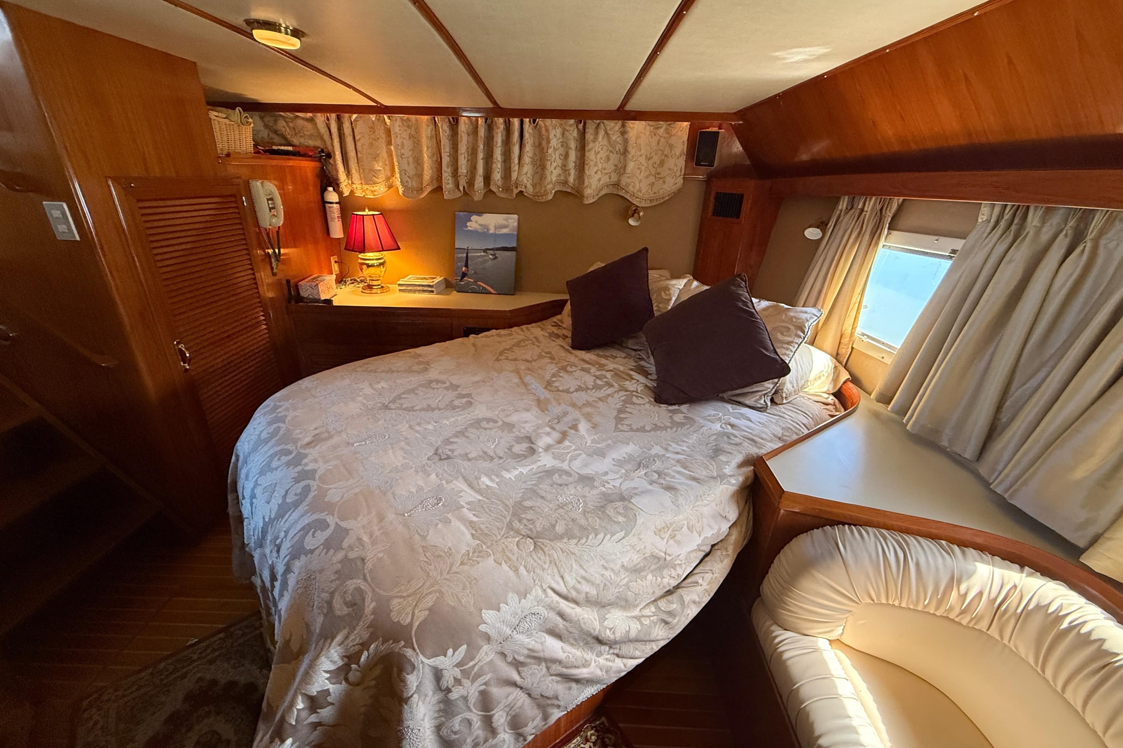 Cozy bedroom interior of 1987 PT Sundeck yacht with elegant bedding and warm lighting.
