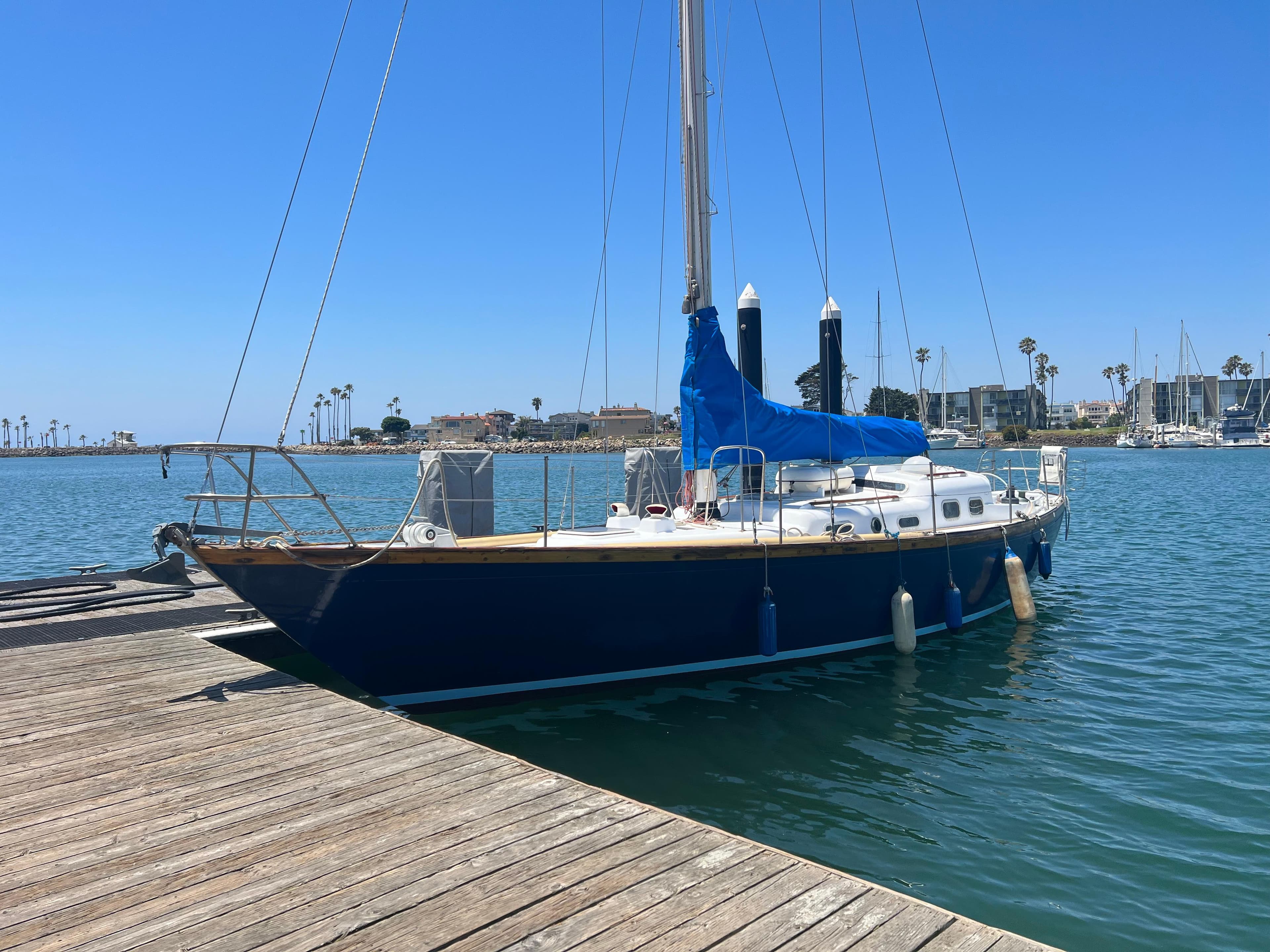 1977 Van De Stadt Rebel 42 sailboat docked in a sunny marina.