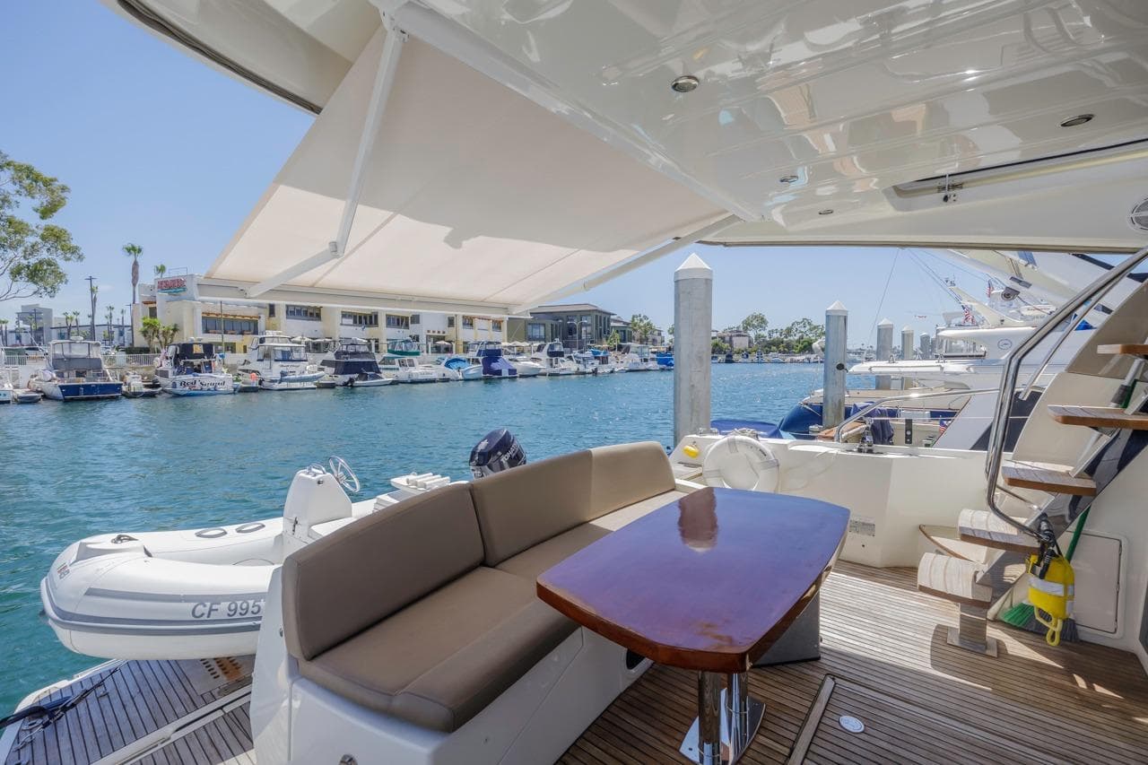 2015 Prestige 500FB yacht deck with seating, table, and marina view.