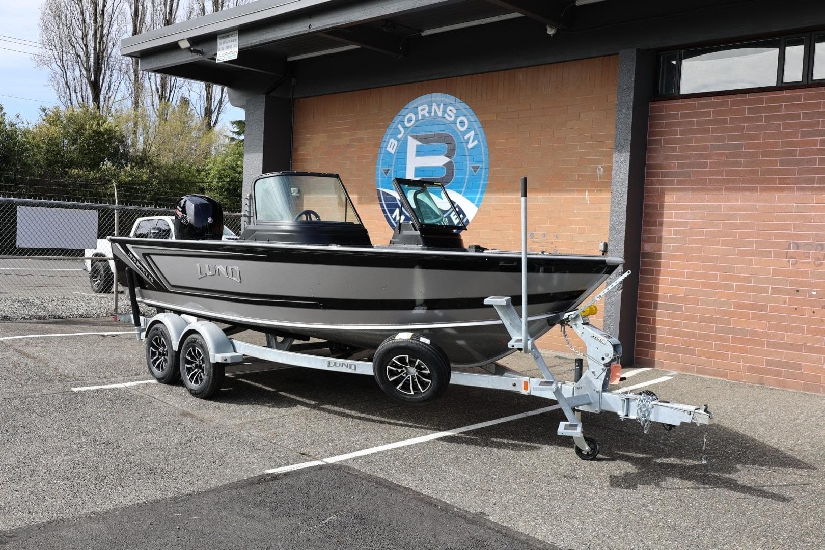 2026 Lund 1875 Impact XS Sport boat on trailer, parked outdoors.