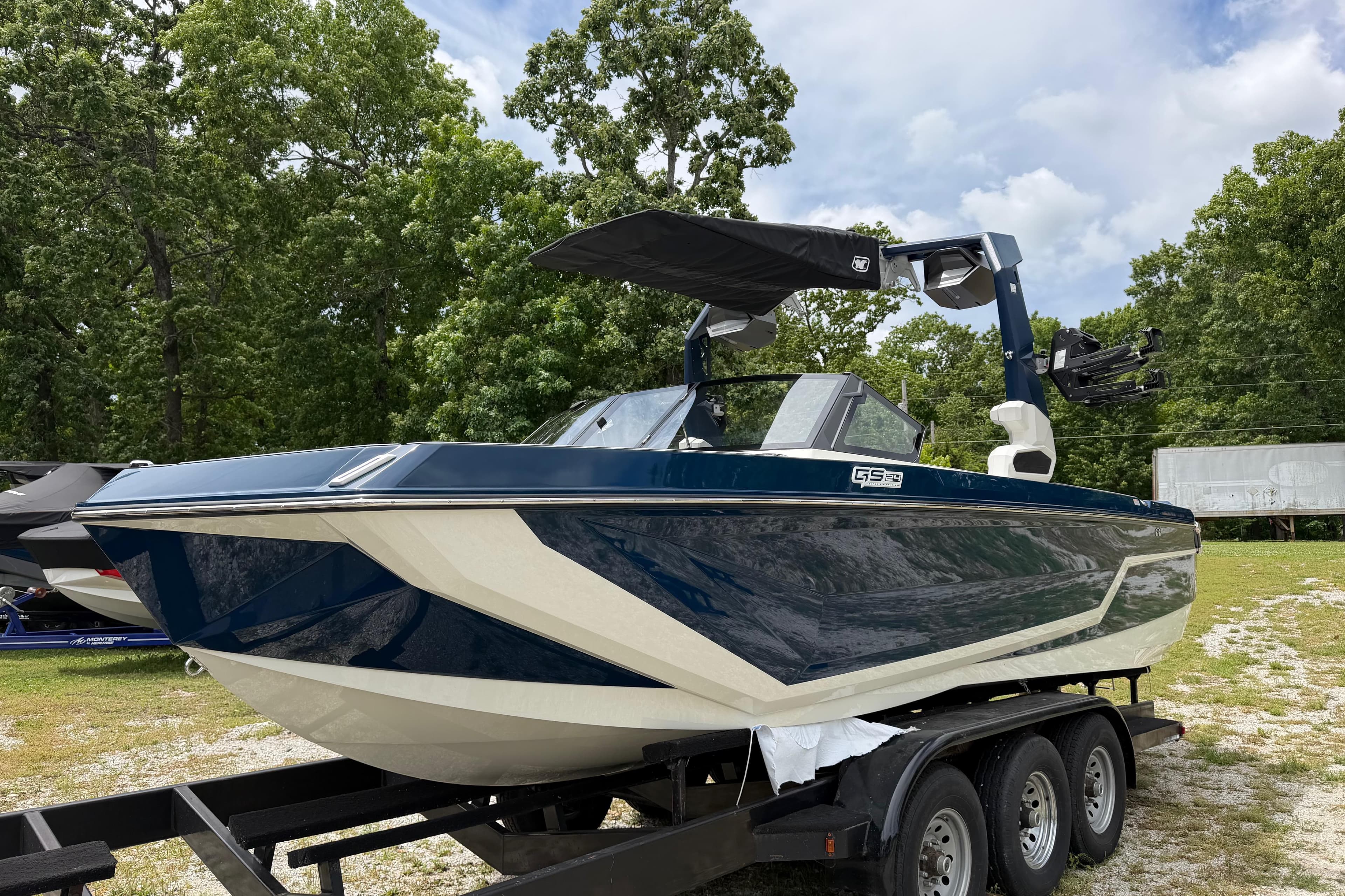 2026 Nautique Super Air Nautique GS24 boat on trailer, surrounded by trees.