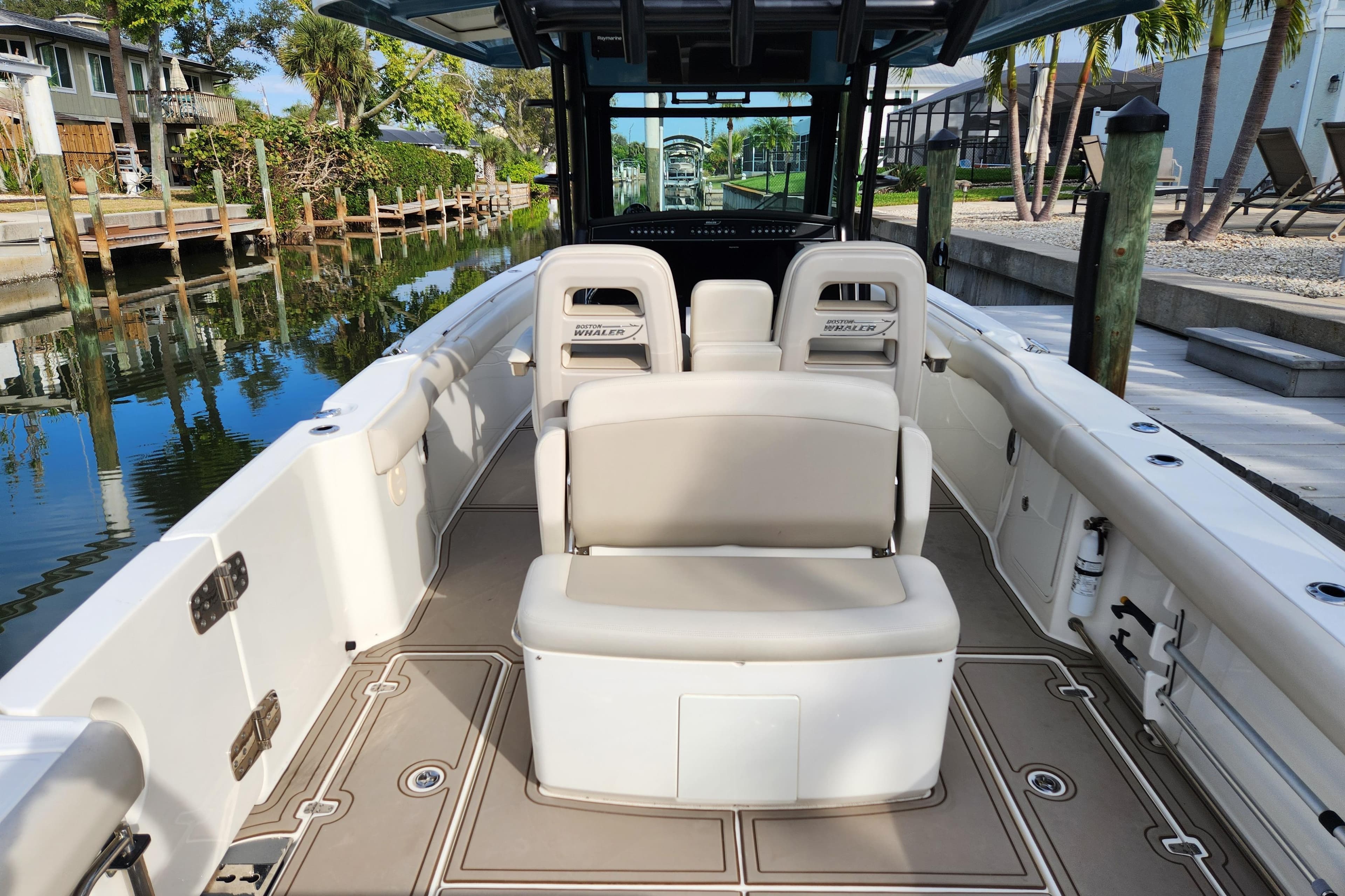 2022 Boston Whaler 330 Outrage boat interior with seating and console, docked by a canal.