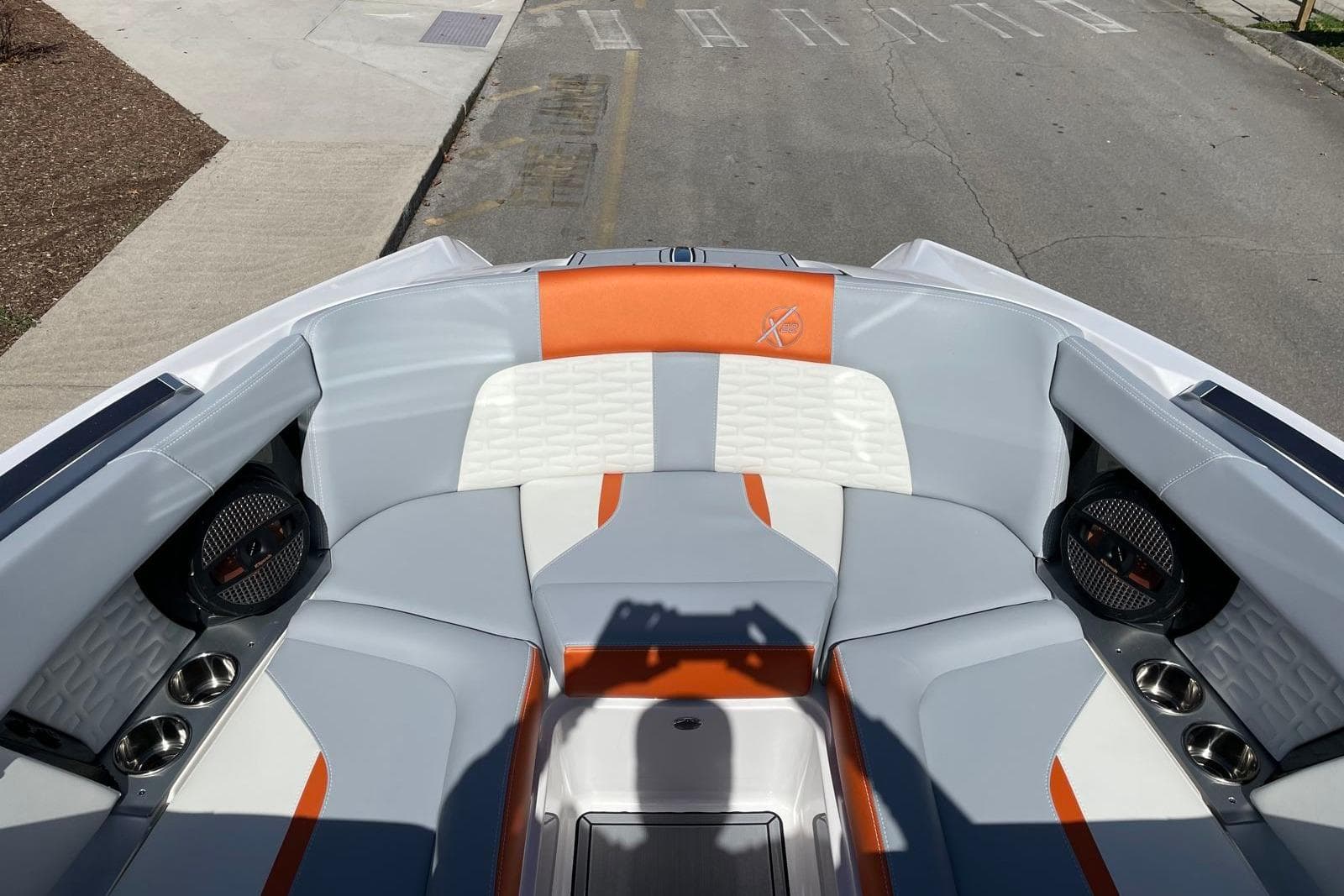 2024 MasterCraft X22 boat interior with orange and gray seating, cup holders, and speakers.