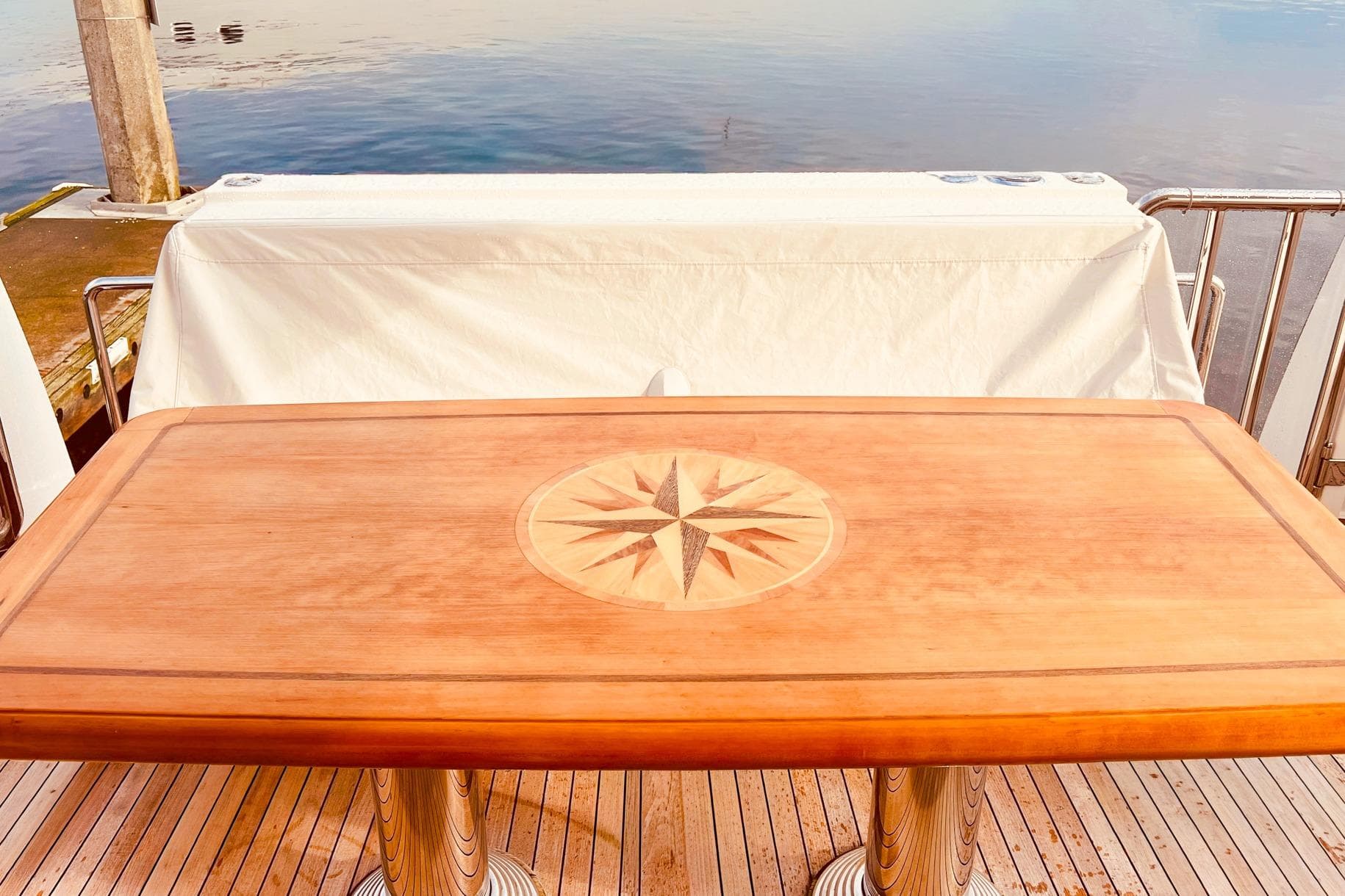 Wooden table with compass design on a 2001 Nordlund Enclosed Command Bridge yacht deck.