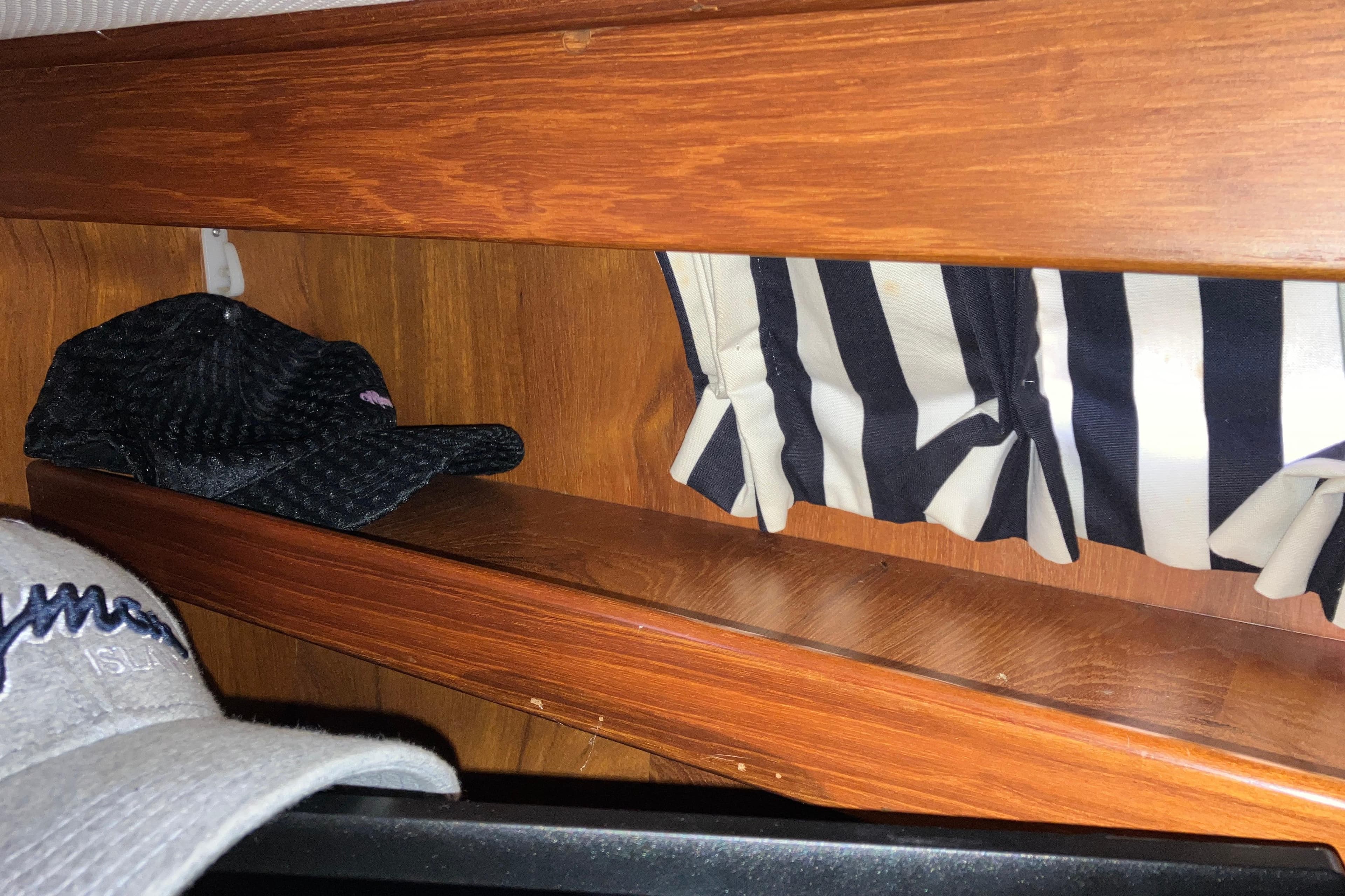 Wooden interior shelf with hats and striped curtain on a 1987 President 37 Sundeck yacht.