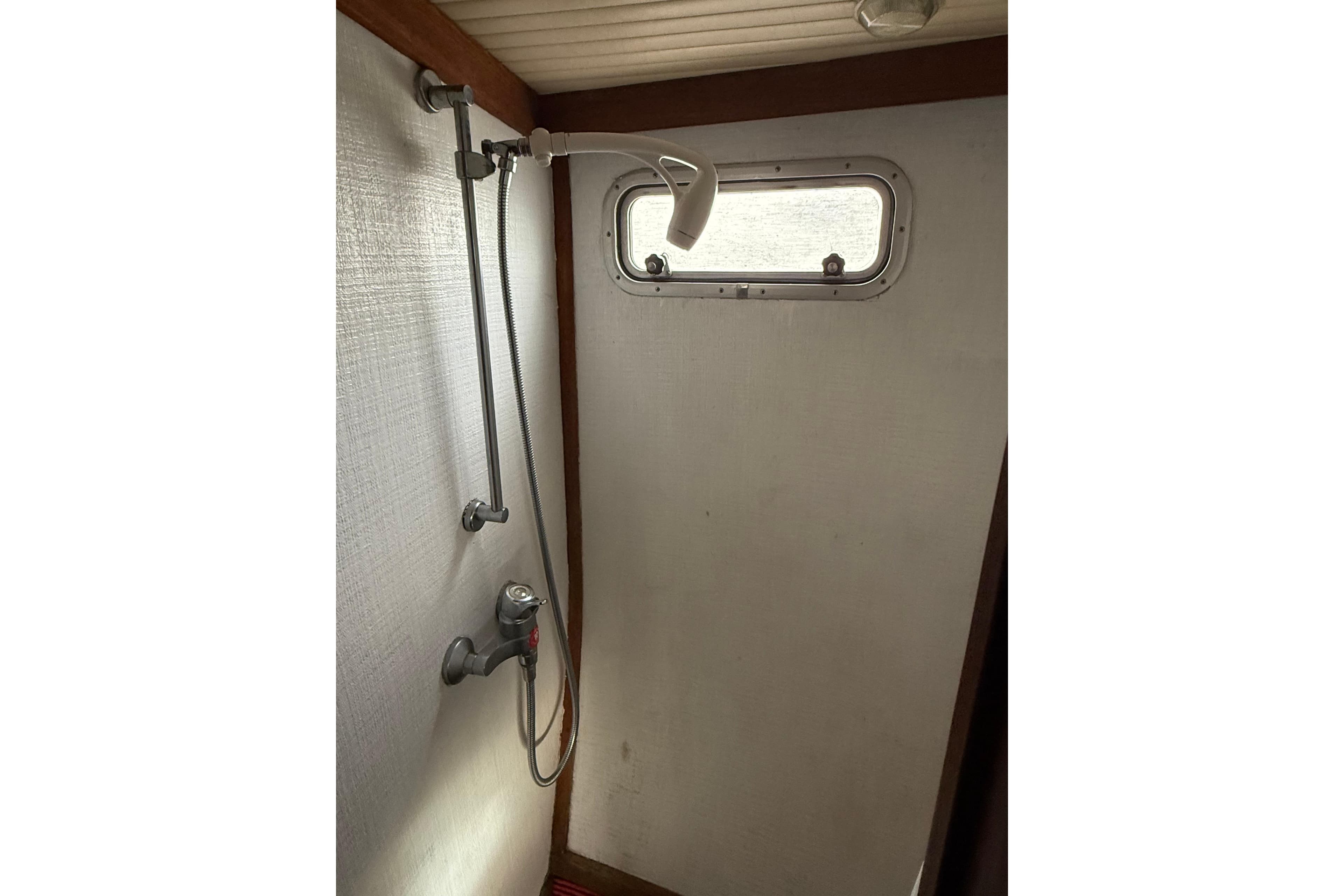 1980 Nauticat Pilothouse shower area with window and adjustable showerhead.