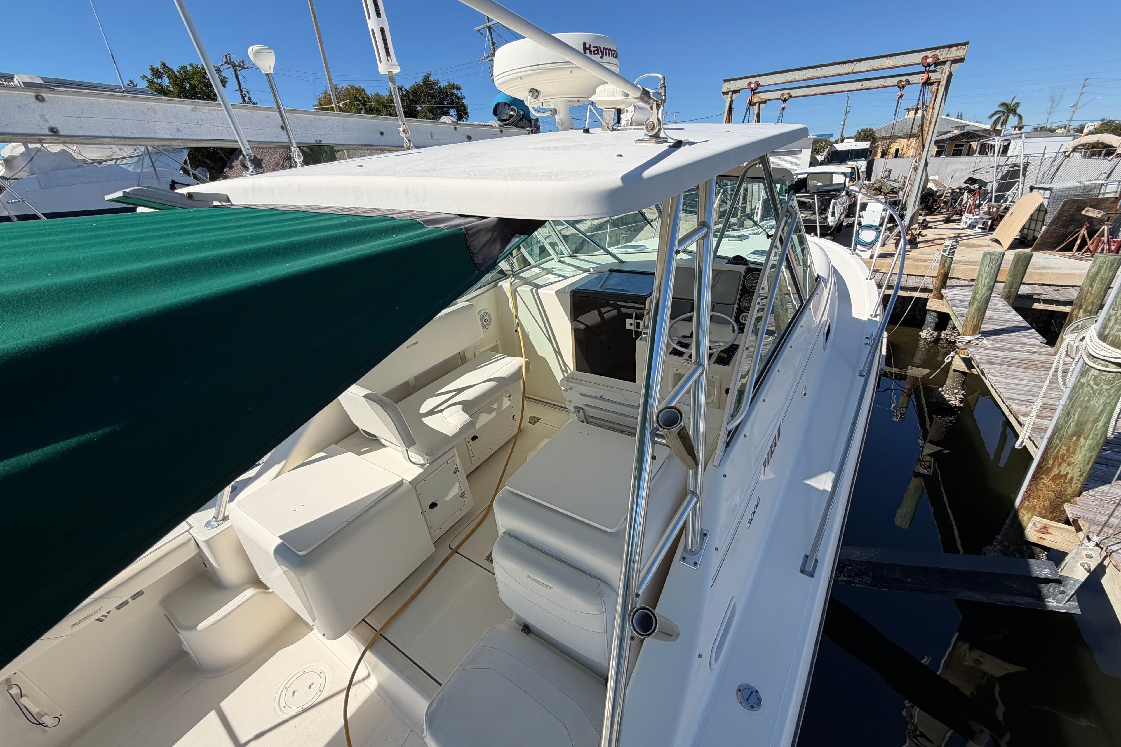 2001 Pursuit 3000 Express boat docked, featuring spacious seating and green canopy.