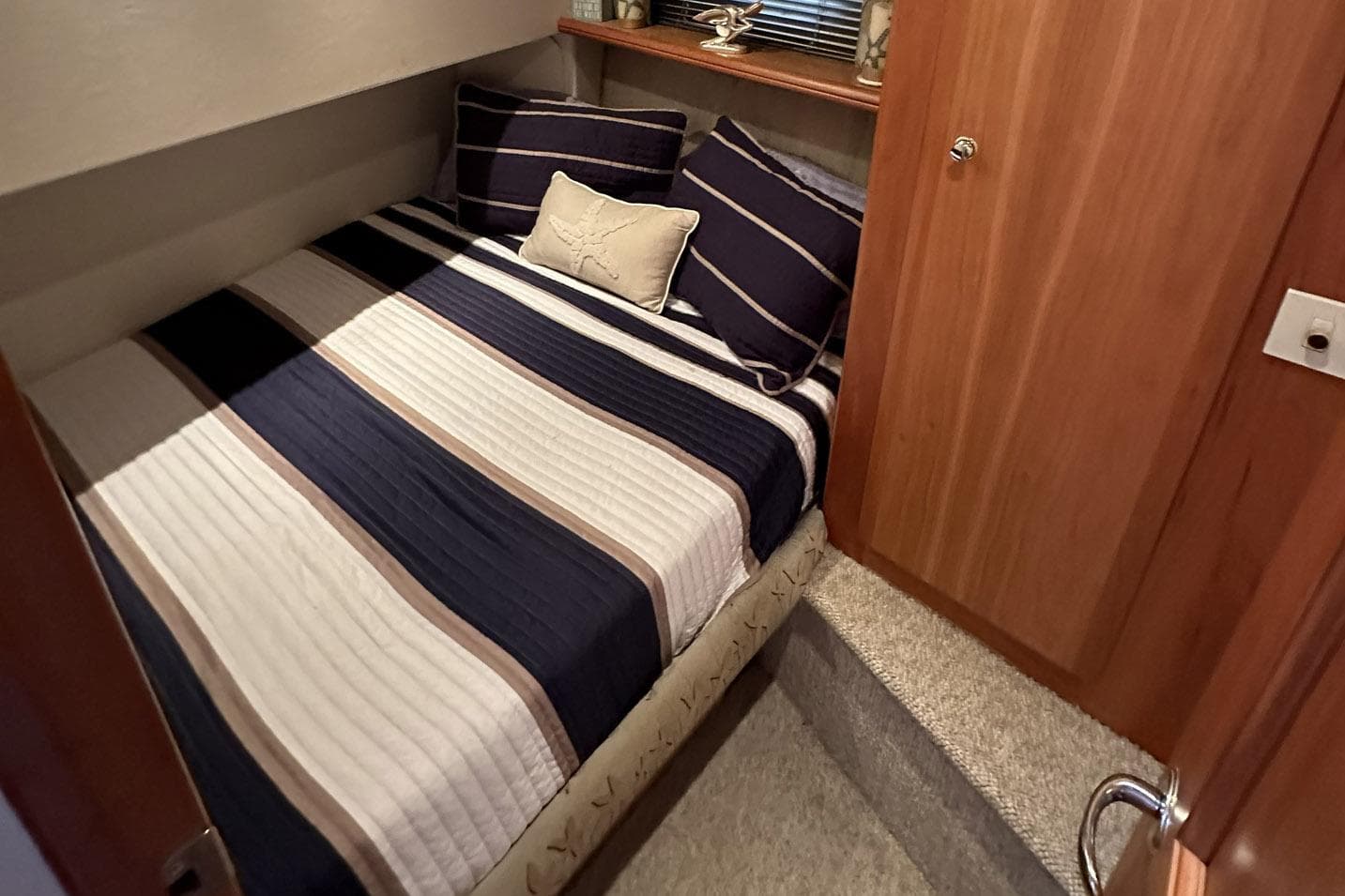 Cozy bedroom interior of 2001 Silverton 42 Convertible yacht with striped bedding.