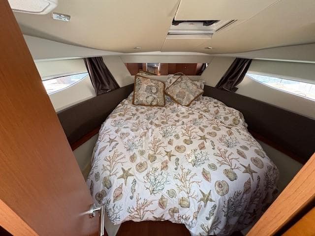2013 Jeanneau NC11 cabin with nautical-themed bedding and cozy interior.