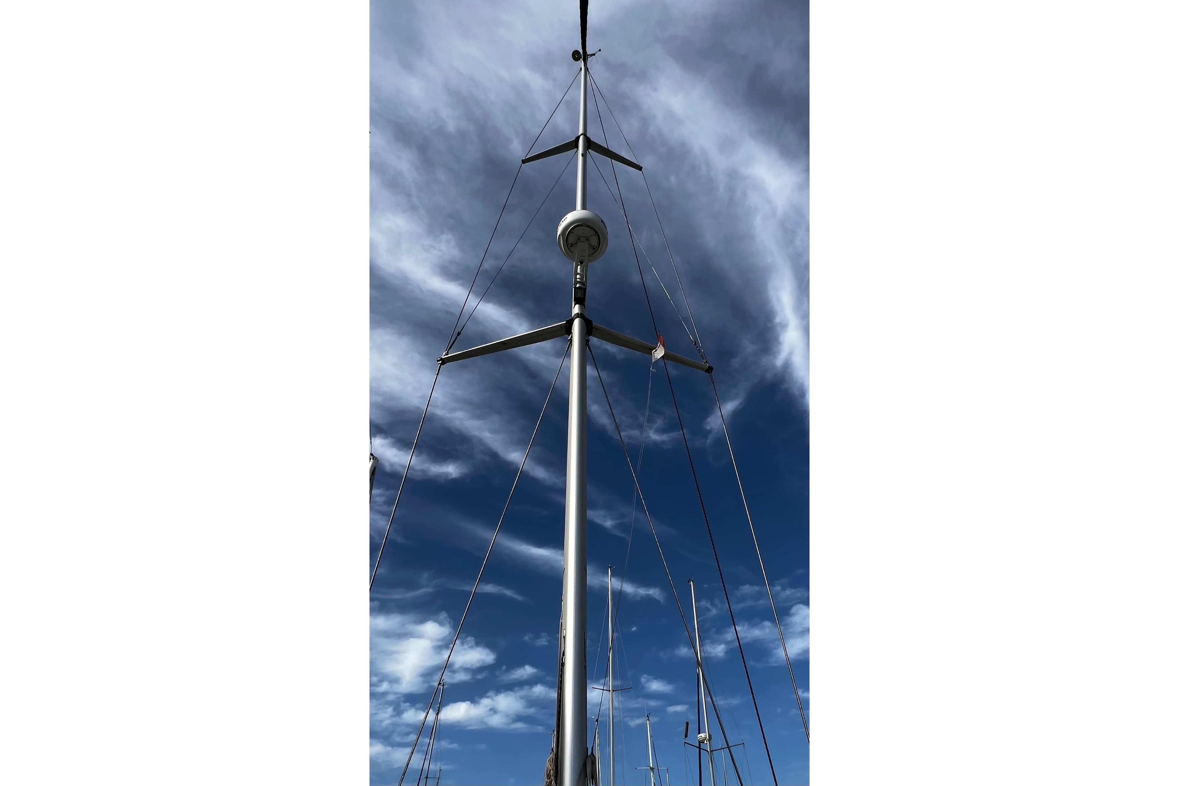 Mast of 2007 Bavaria 44 Vision sailboat against a cloudy blue sky.