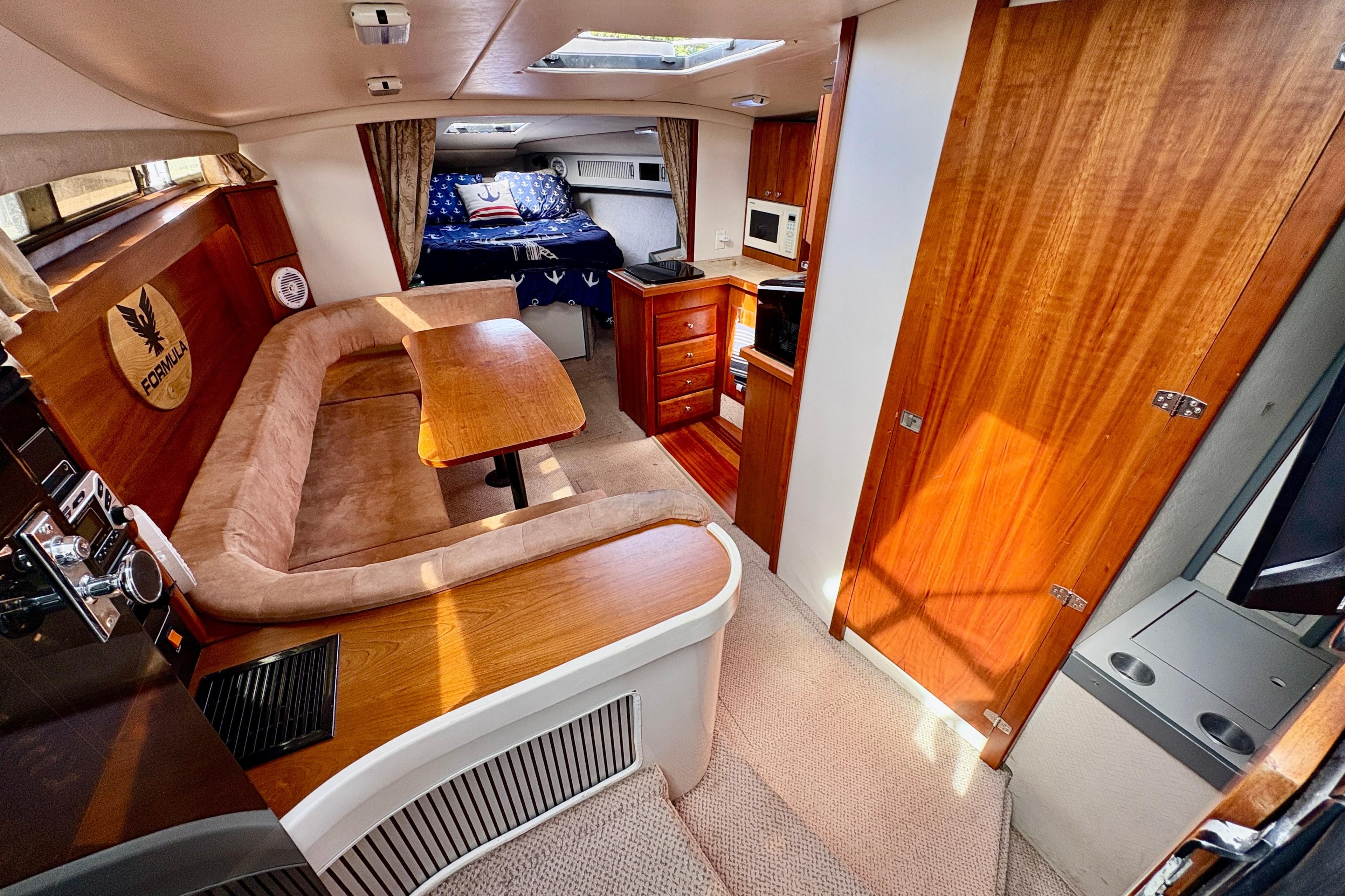 1989 Formula 35 PC yacht interior with cozy seating, wooden cabinetry, and a compact kitchen area.