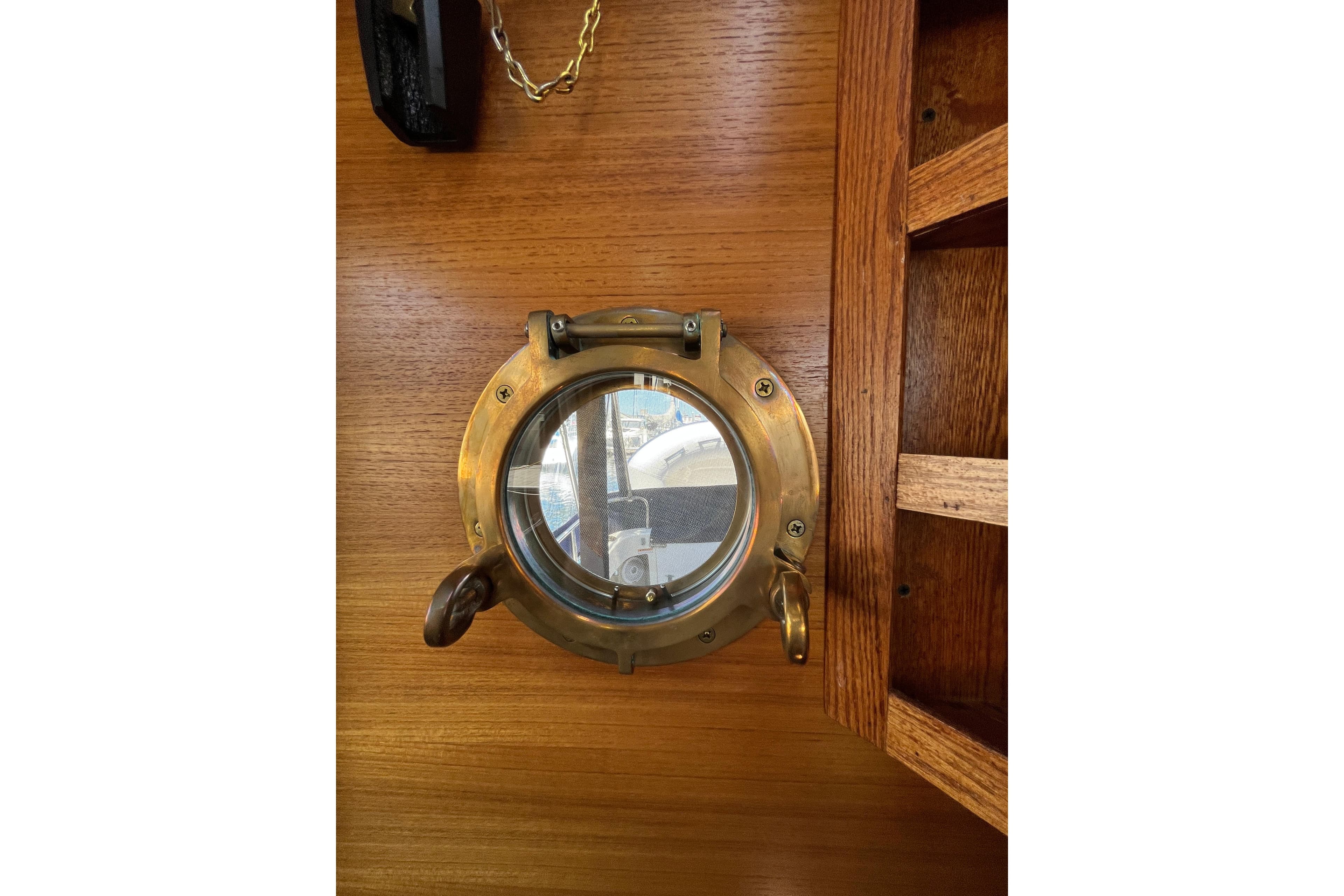 Brass porthole on 2017 Ranger Tugs R-27 boat, wooden interior detail.