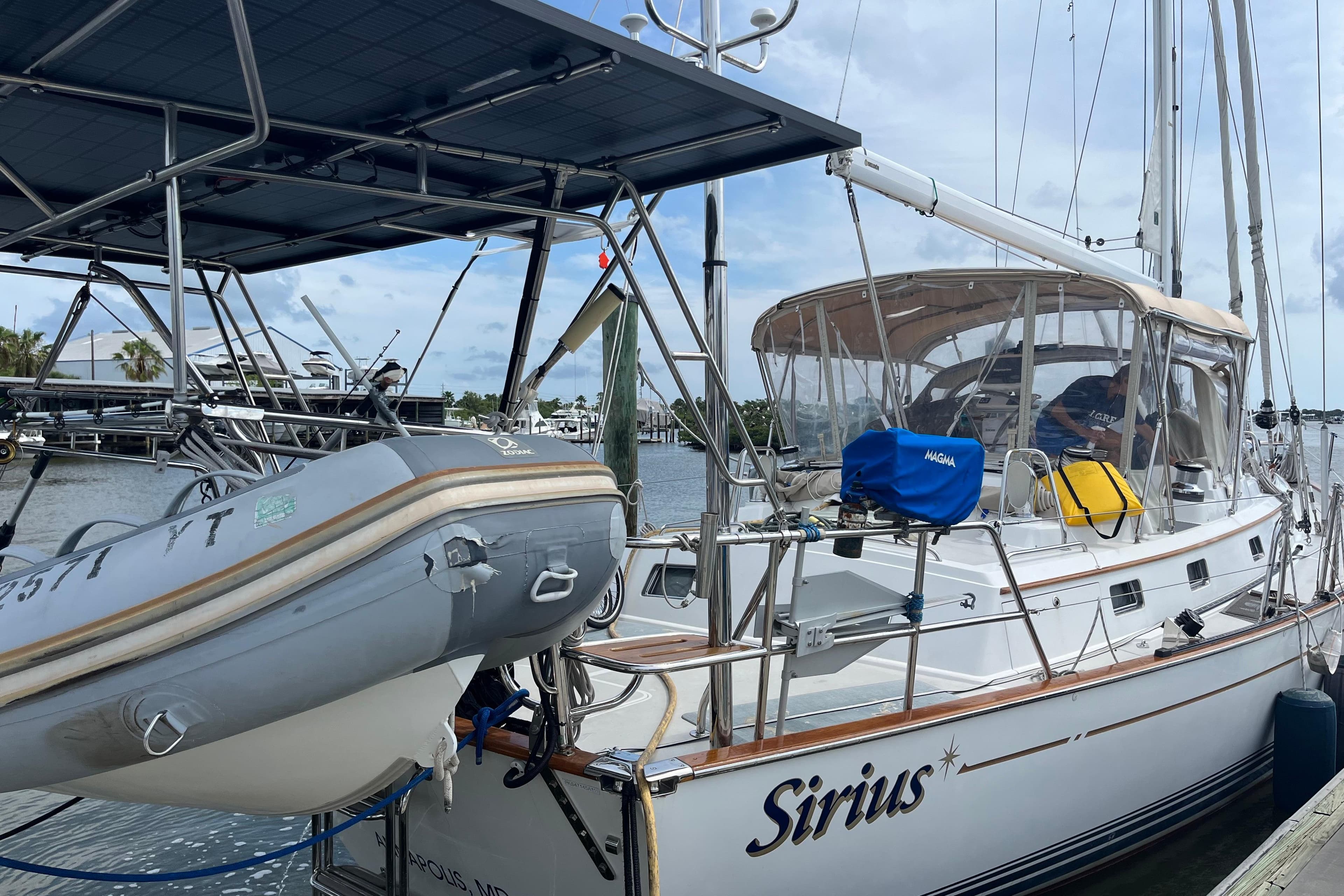 Passport 470 Center Cockpit sailboat docked, featuring a dinghy and solar panels, 2011 model.