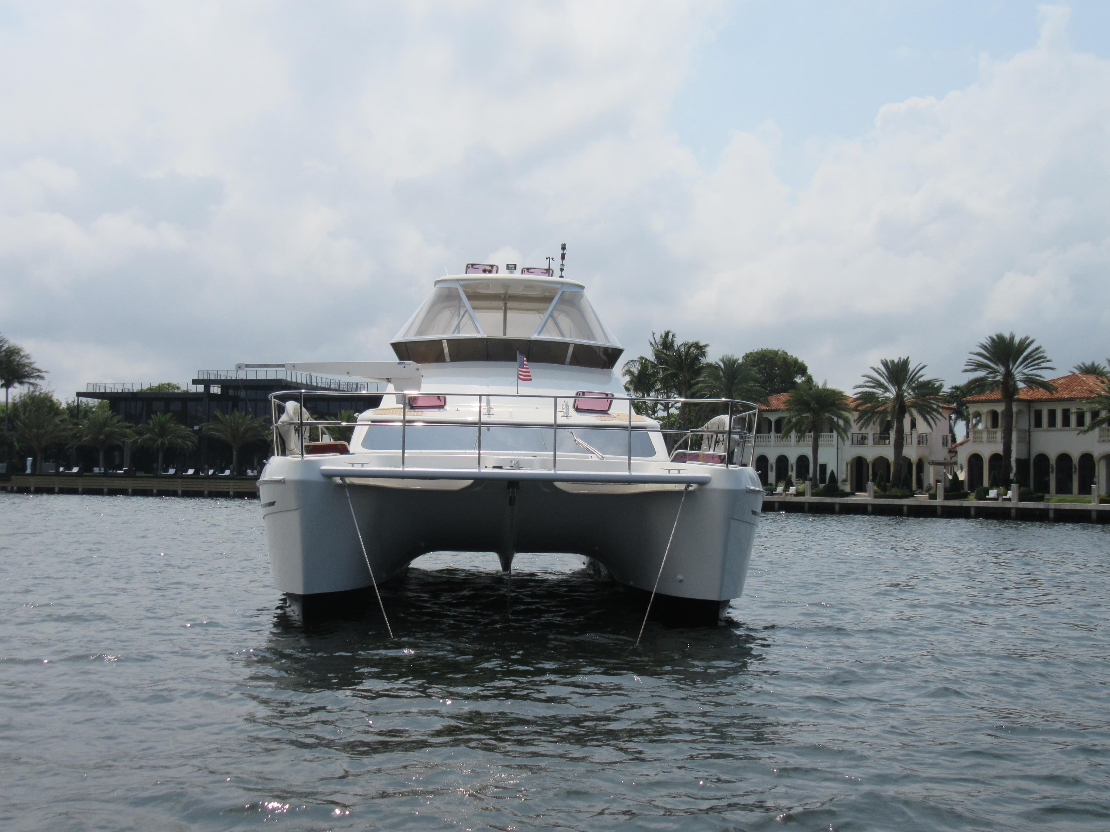 Africat Marine 420 catamaran, 2008 model, on water near luxury waterfront homes.