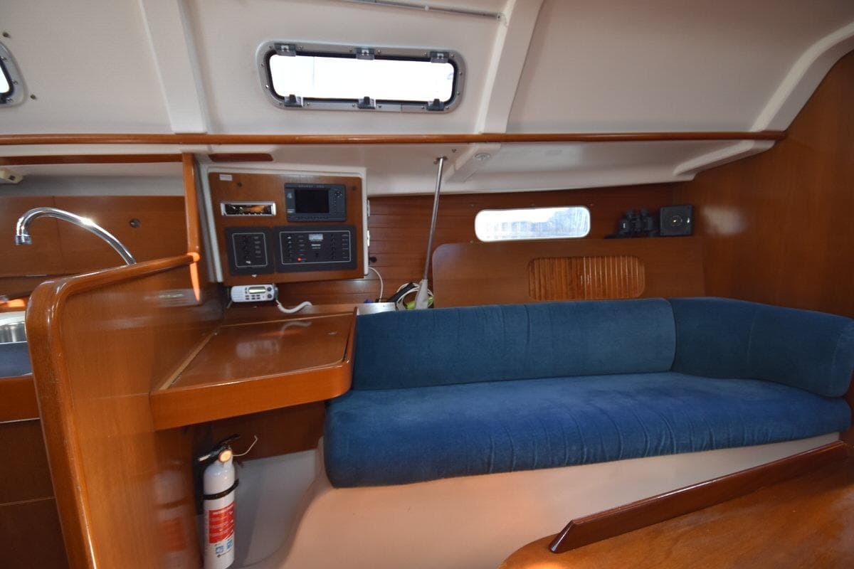 Interior of 1996 Beneteau Oceanis 321 sailboat with blue sofa and wooden cabinetry.