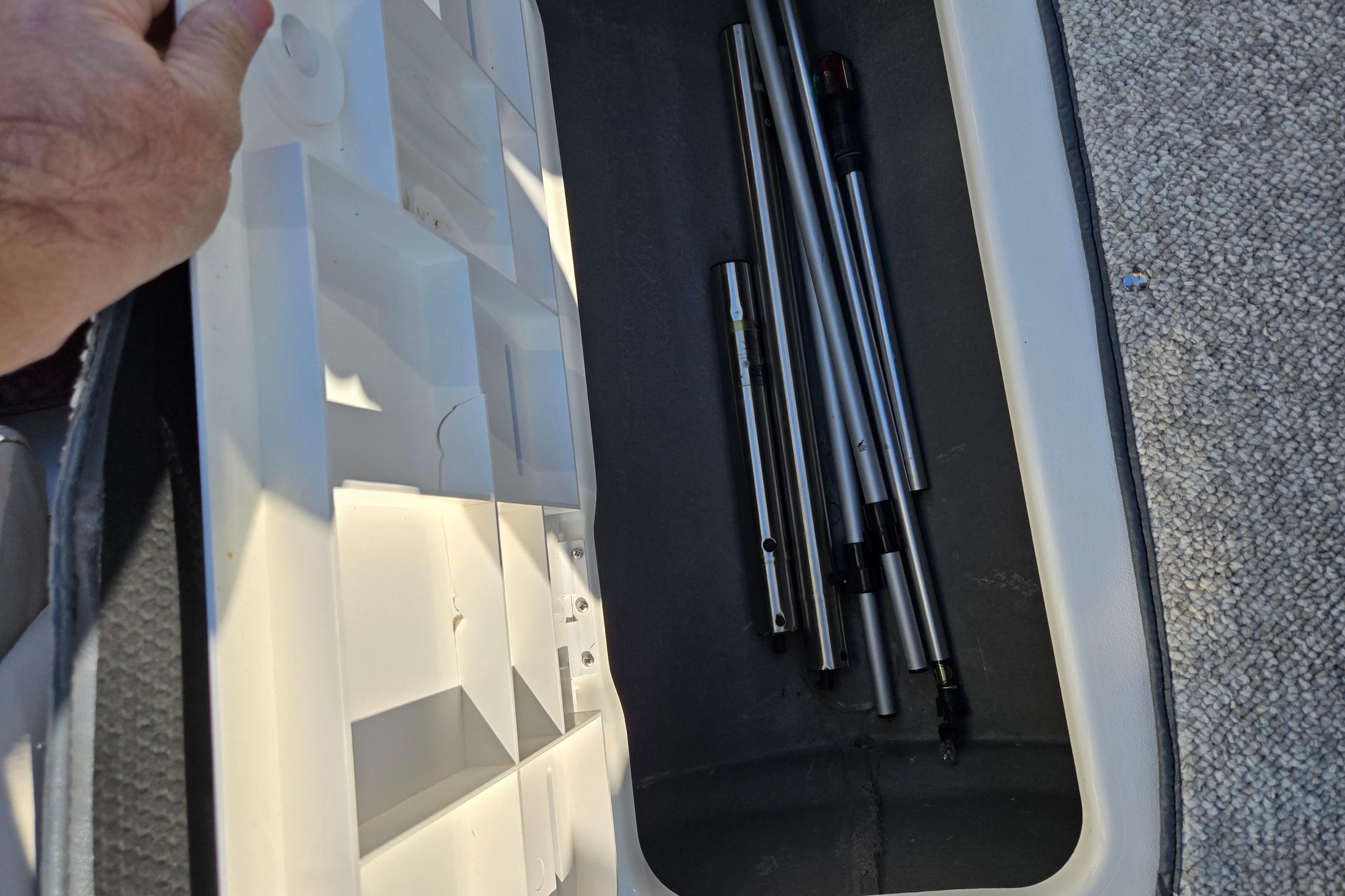 Storage compartment in a 2007 Glastron GT 205 Ski & Fish boat with metal rods.