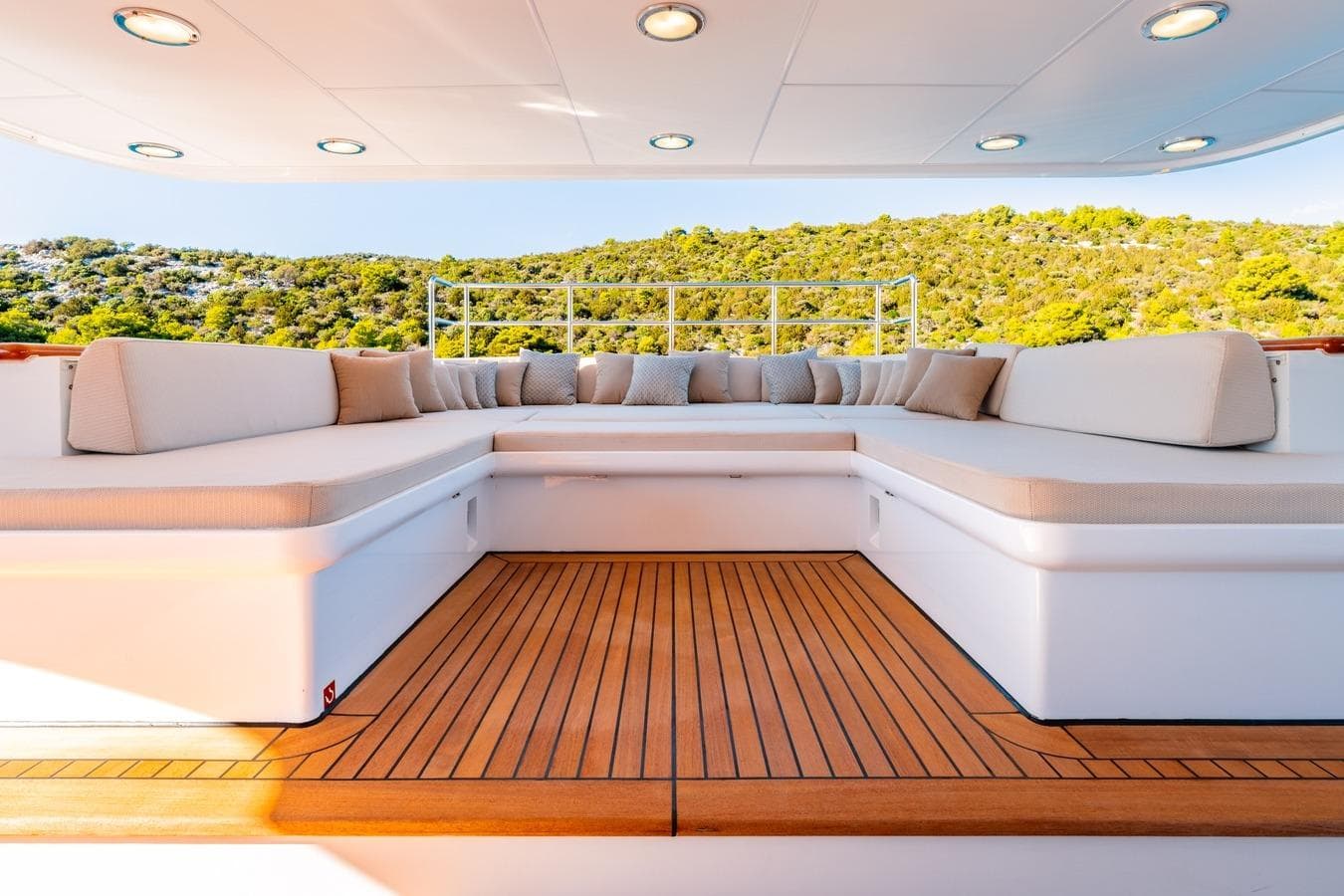 Luxurious seating area on 1983 Feadship 55 yacht with scenic forest backdrop.