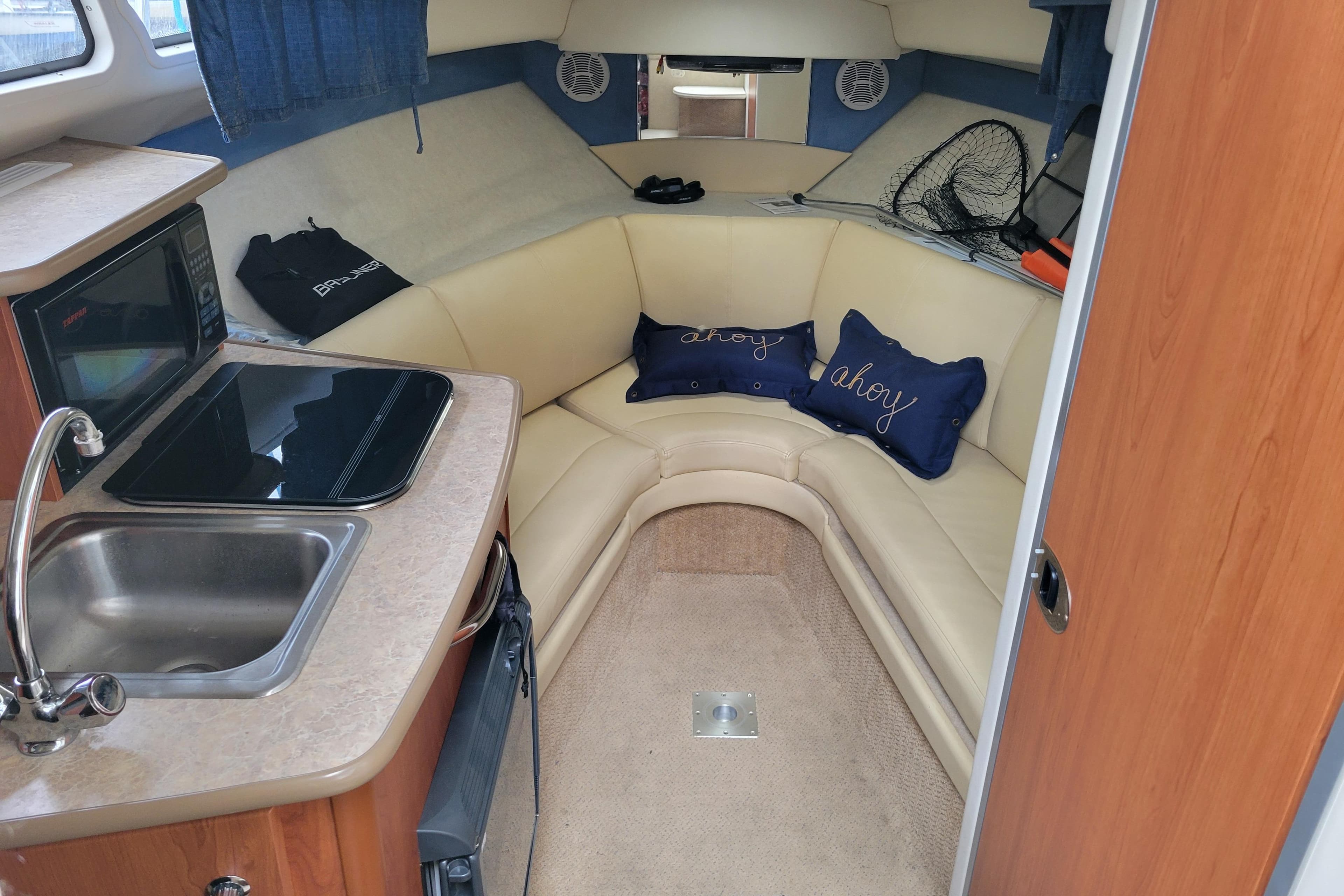 Interior of 2007 Bayliner 245 Cruiser with kitchenette and cozy seating area.