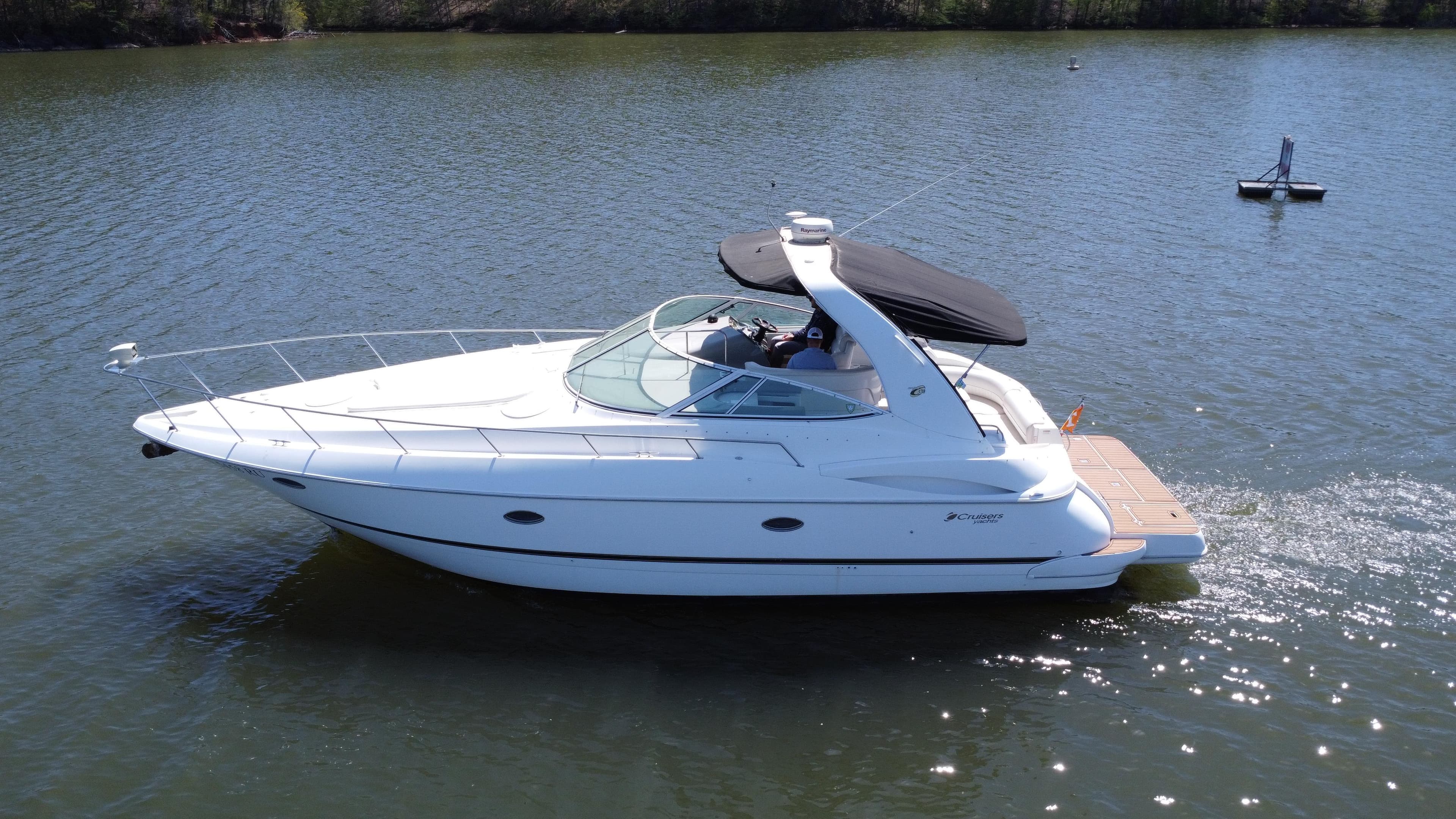 2004 Cruisers Yachts 370 Express on calm water, side view with black canopy.