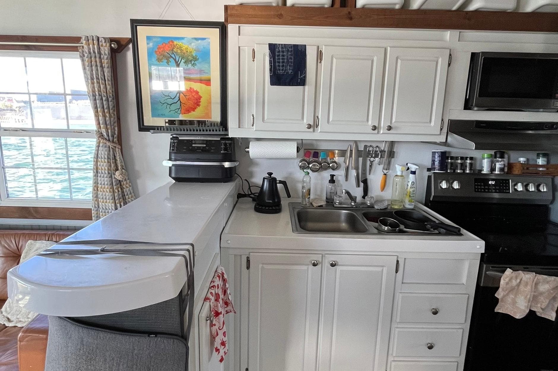 Compact kitchen in 2017 Catamaran Cruisers Aqualodge with white cabinets and appliances.
