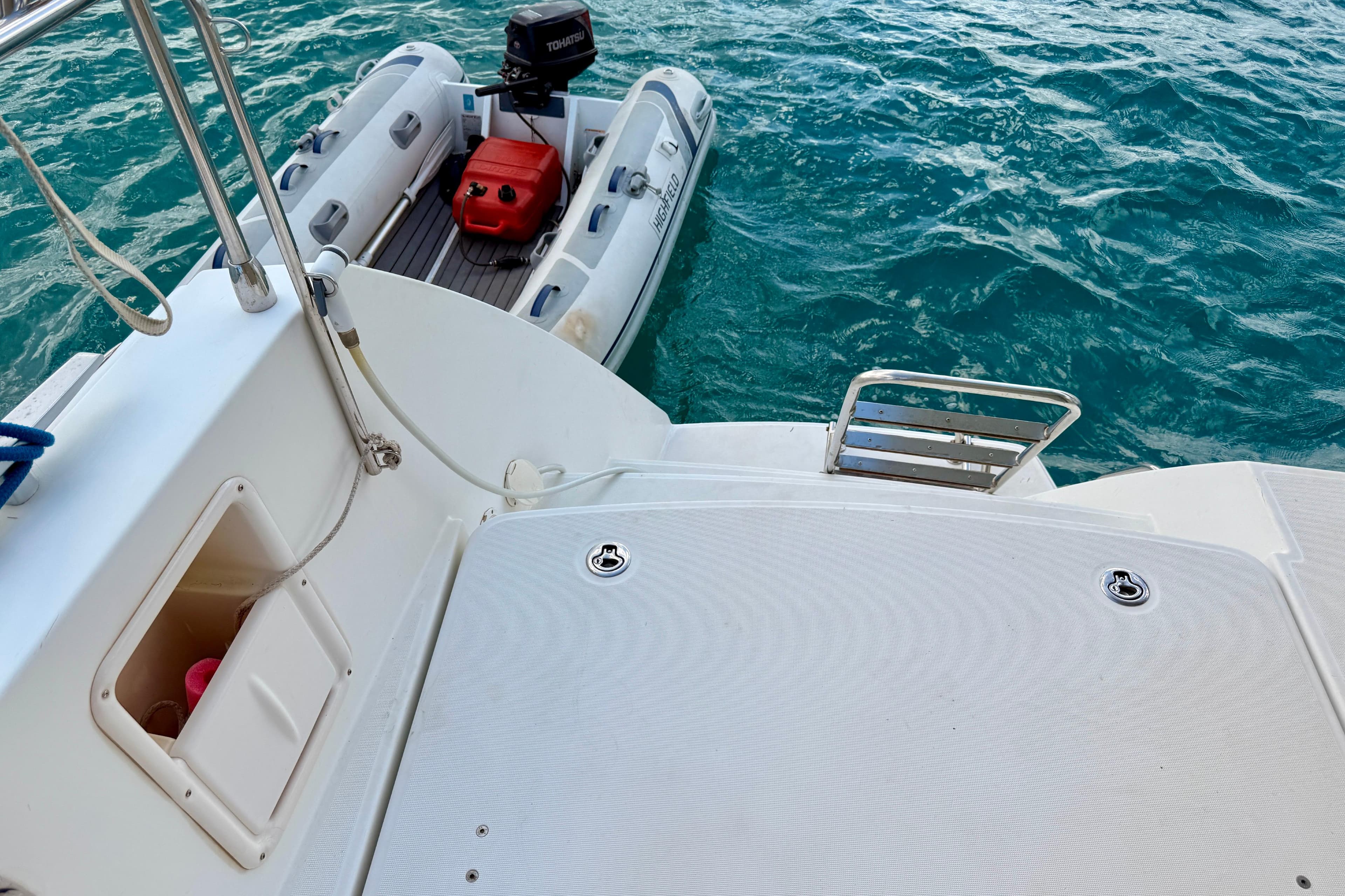Lagoon 450 F yacht deck with attached dinghy on turquoise water, 2012 model.