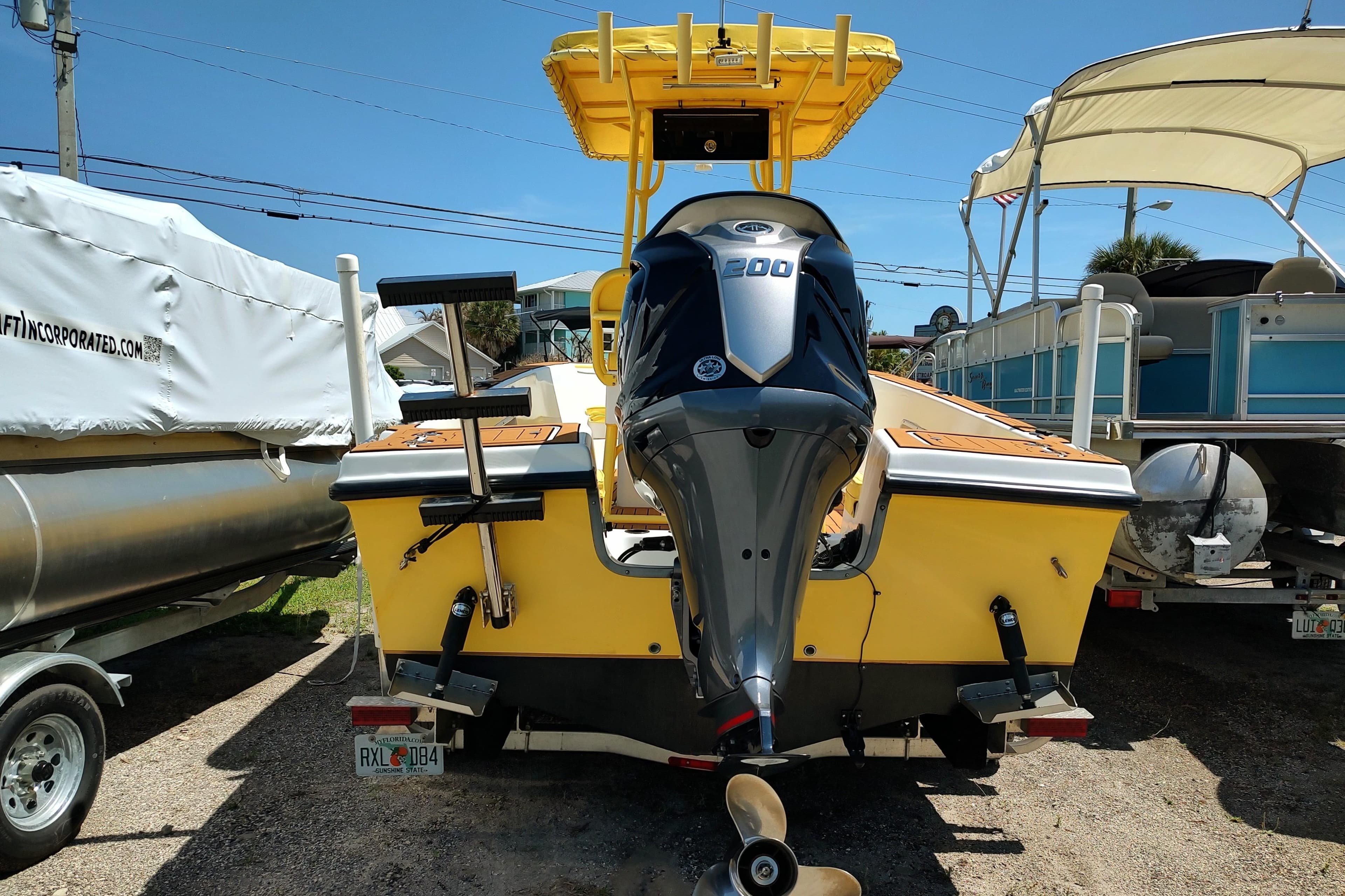 Yellow 2004 Angler 204 Center Console boat with outboard motor, parked outdoors.