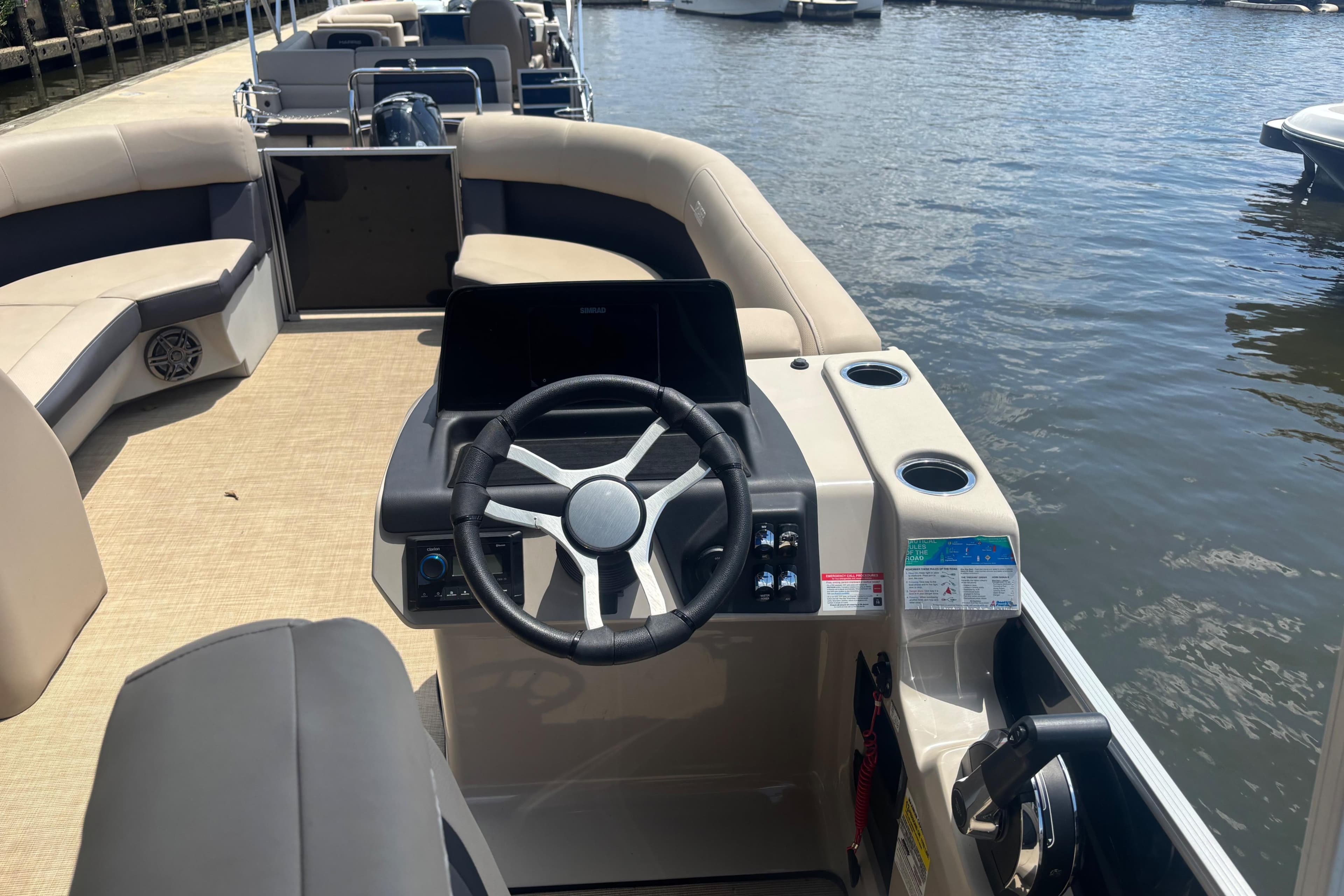 2024 Harris HCX23 boat interior with steering wheel, seating, and water view.