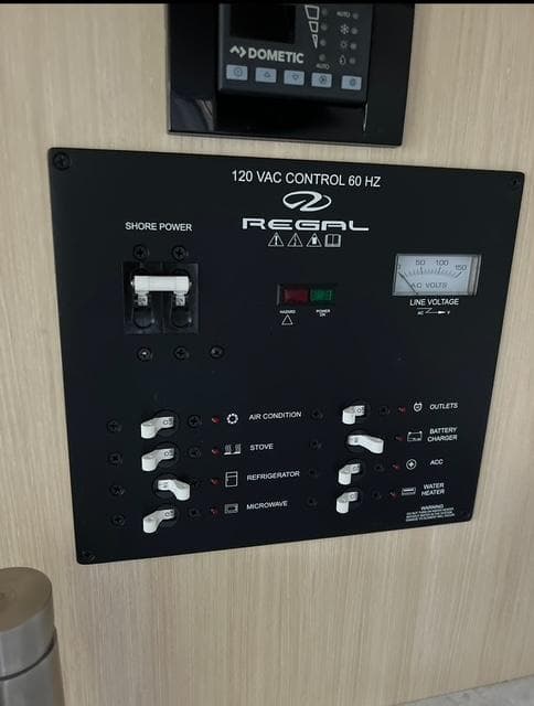 2024 Regal 26 X control panel with switches for air conditioning, stove, refrigerator, and microwave.