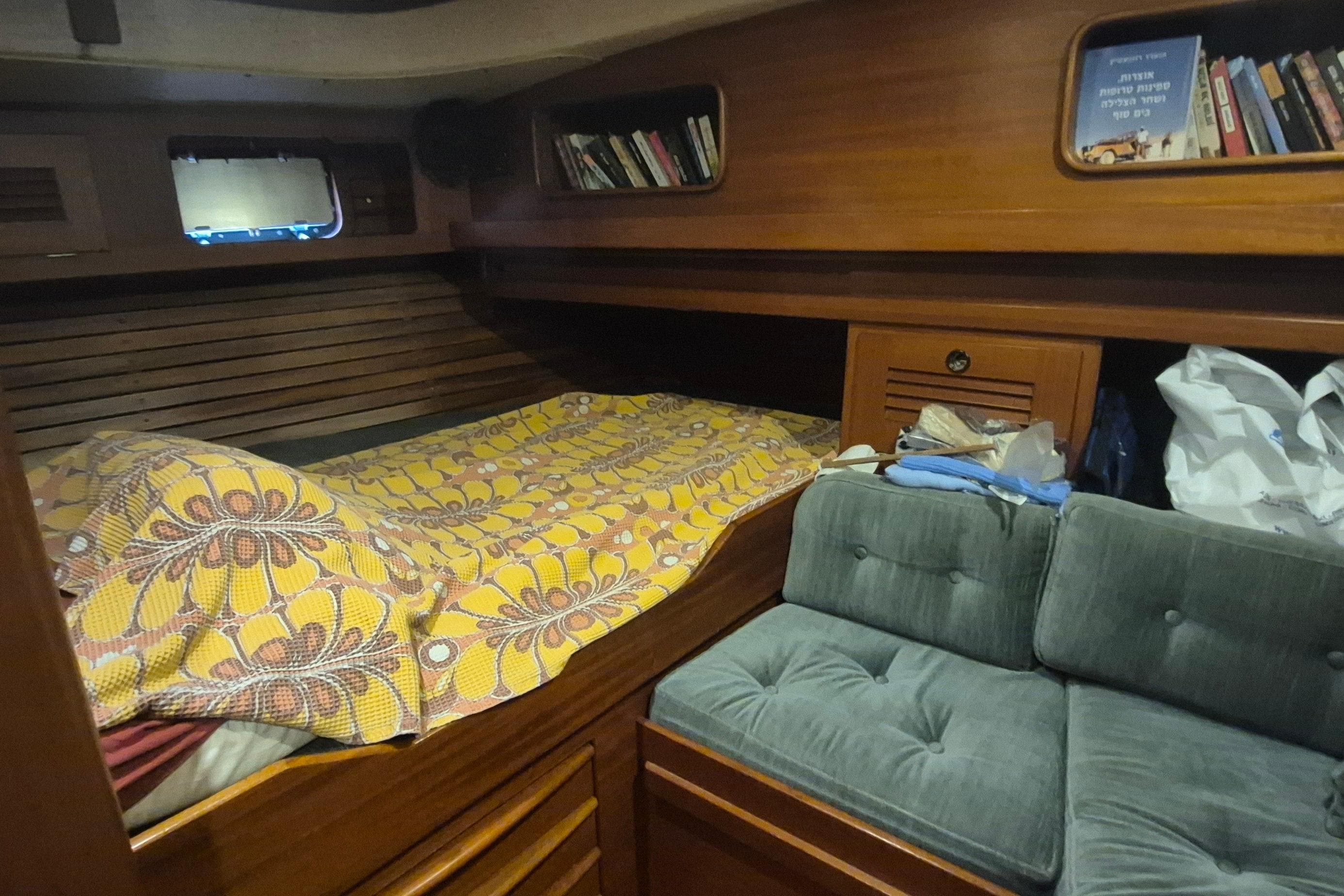 Cozy cabin interior of 1986 Hallberg-Rassy 49 sailboat with bed and bookshelves.