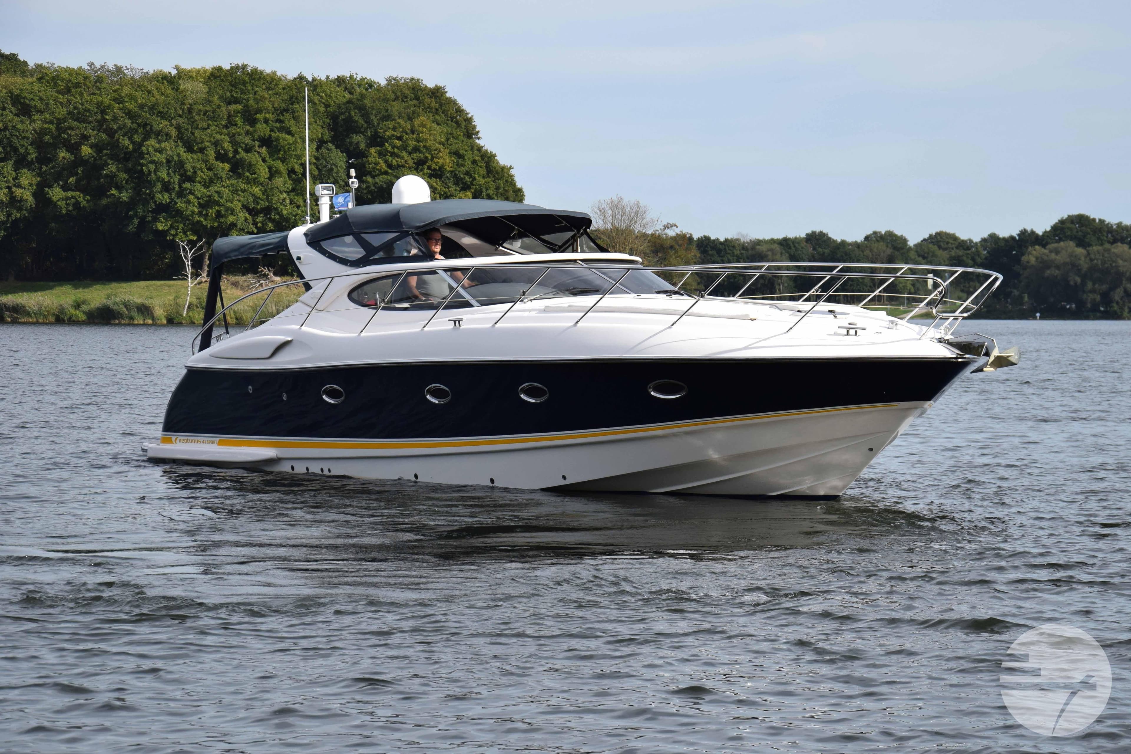 2004 Neptunus 41 Sport yacht cruising on a serene lake with lush green shoreline.