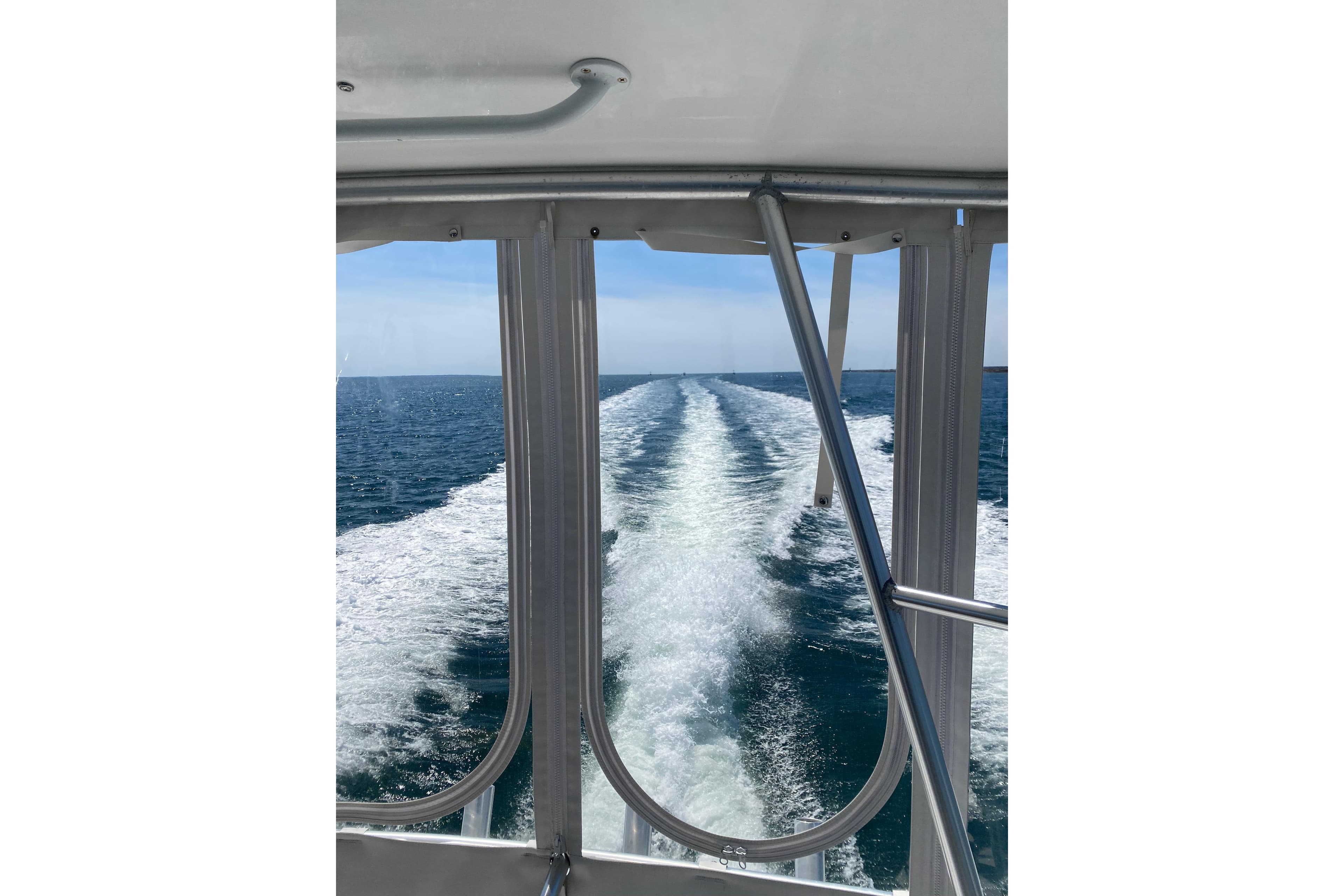View from a 1998 Post 47 Convertible boat, showing ocean wake and clear skies.