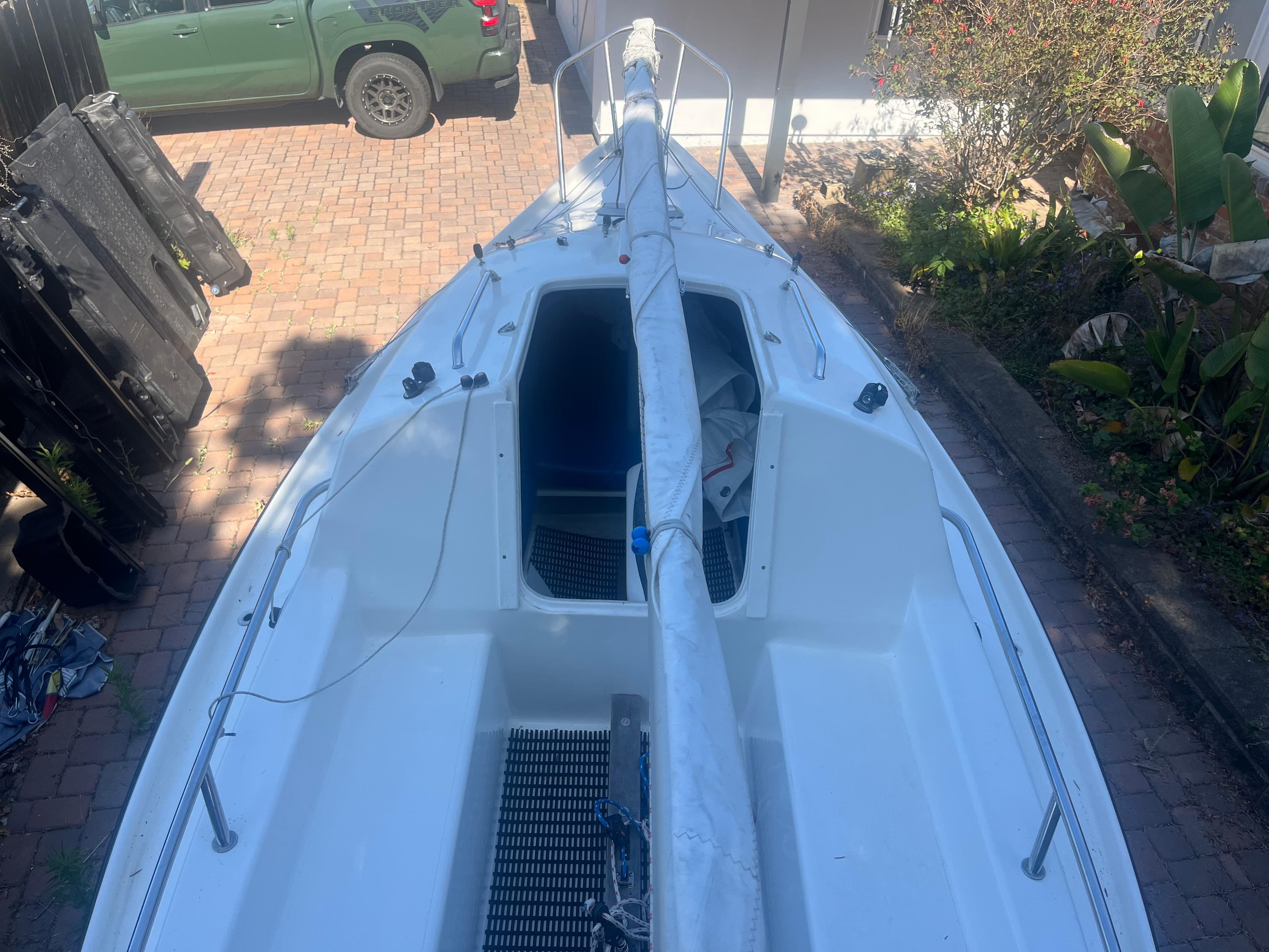 Sailboat Malbec 18, 2023 model, docked on brick driveway with green vehicle nearby.