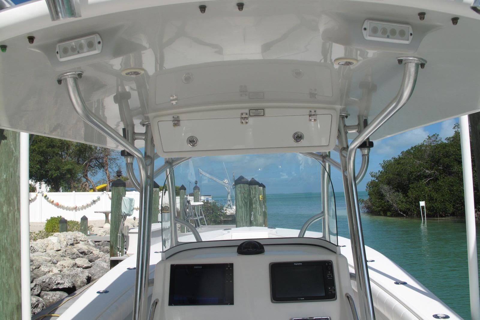 2013 Regulator 32 Forward Seating boat console with electronics, docked by clear water and greenery.