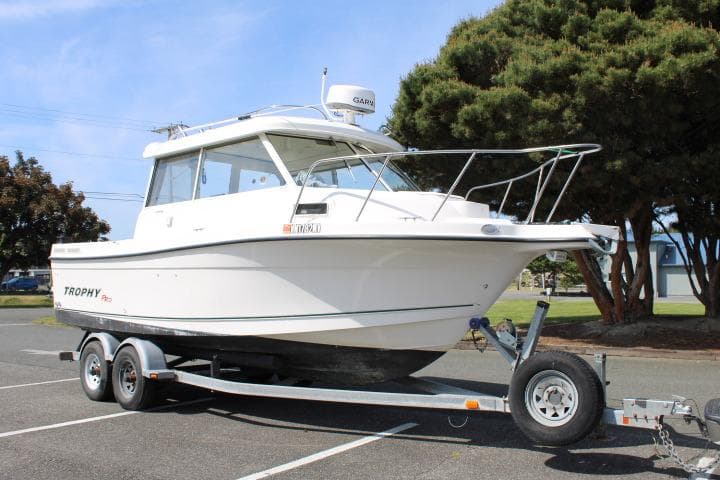 2006 Trophy 2359 Pro boat on trailer, parked outdoors near trees.