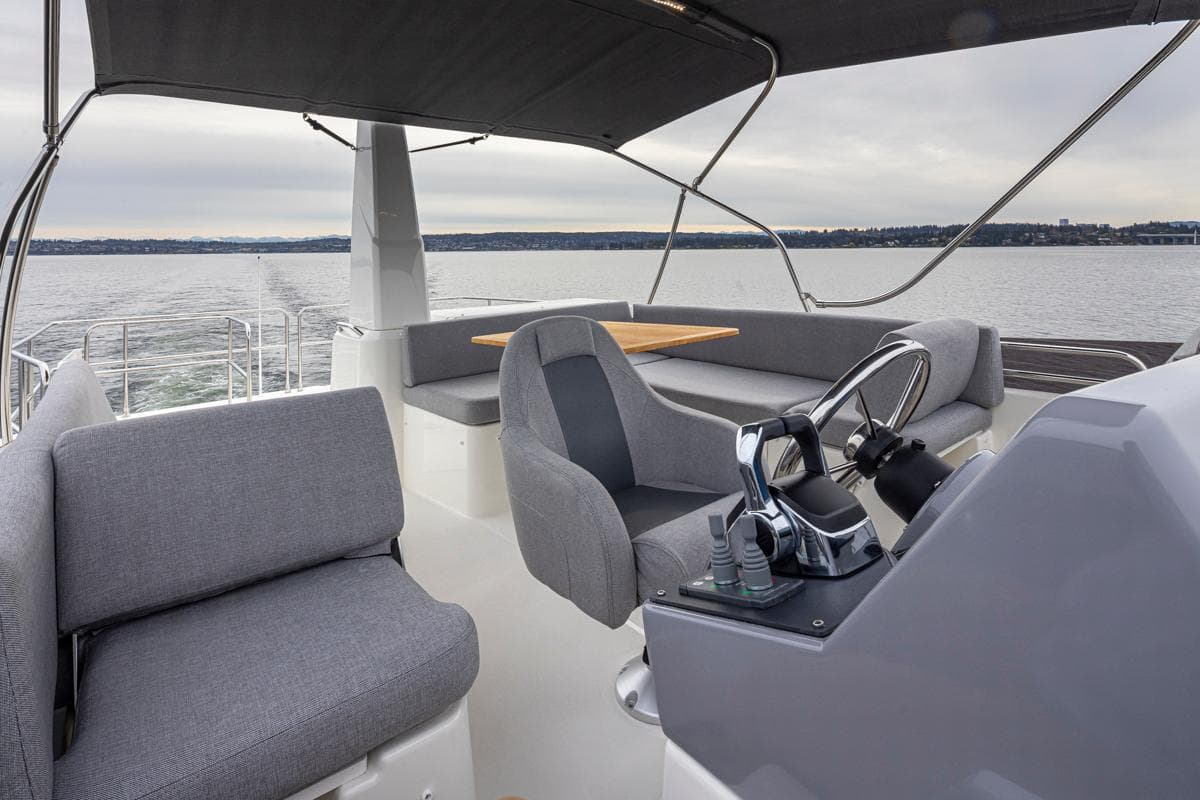 2026 Beneteau Swift Trawler 41 Flybridge with modern seating and steering, cruising on open water.
