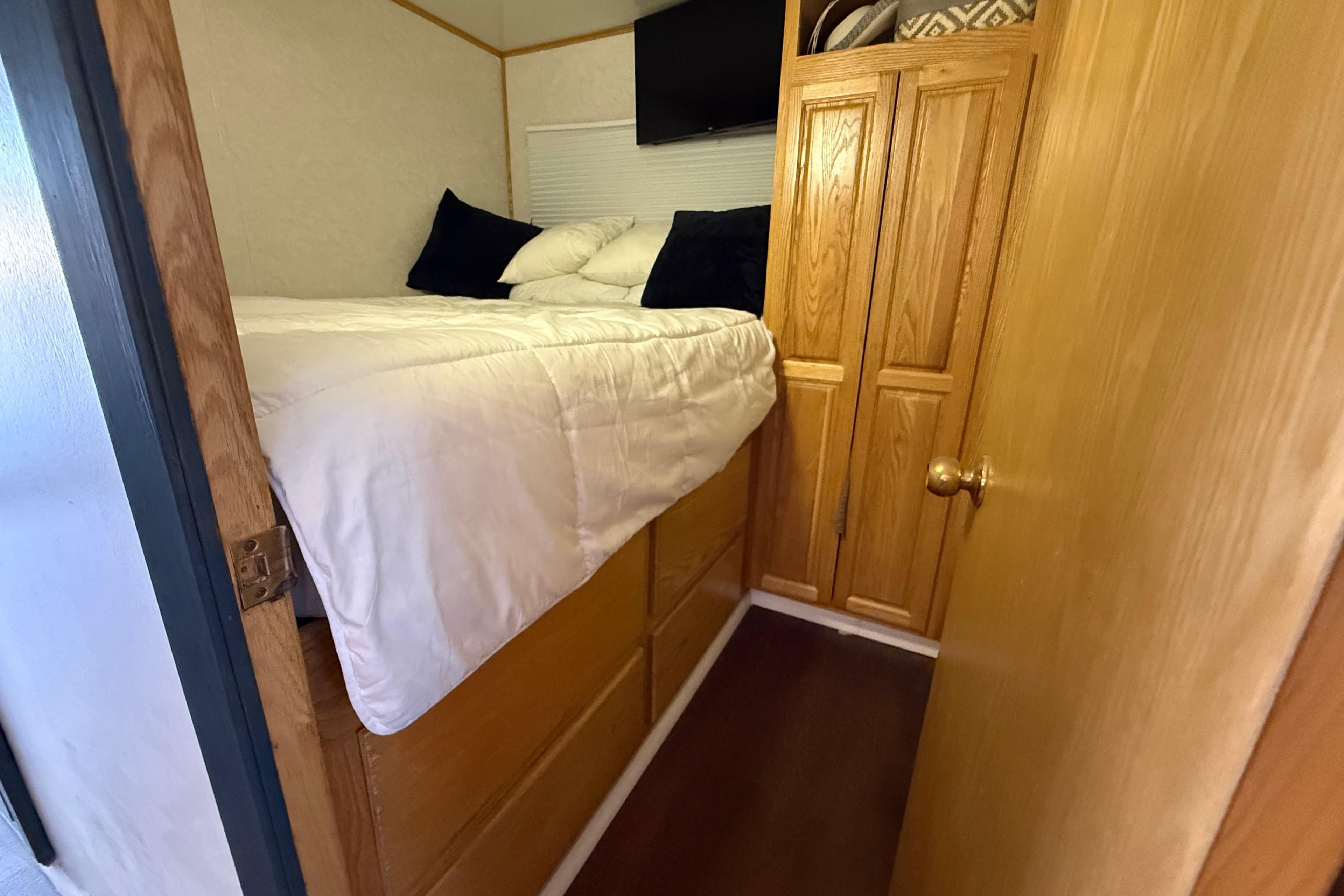 Compact bedroom in 2006 Fun Country SunCountry Arizona Edition RV with wooden cabinetry.