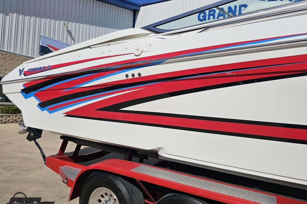 2001 Formula 382 FASTech boat with vibrant red and blue graphics on a trailer.