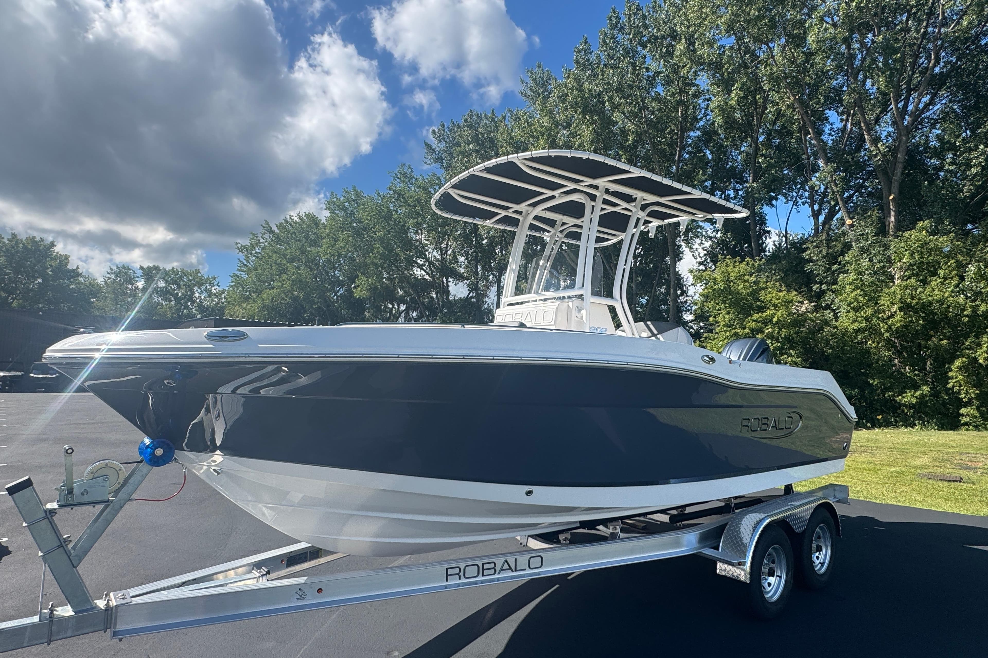 2026 Robalo R202 Explorer boat on trailer, parked outdoors under cloudy sky.